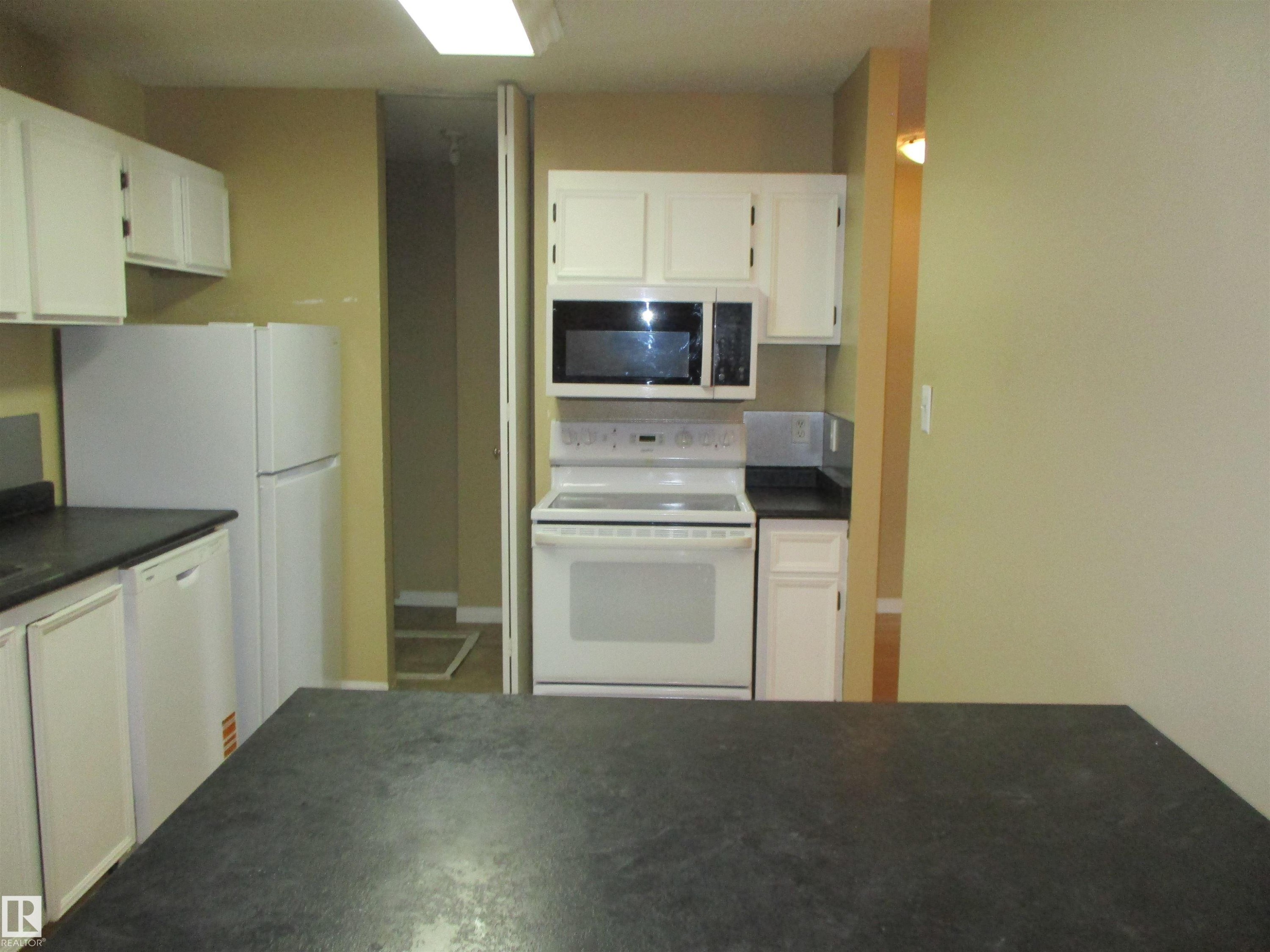 Kitchen featuring dark countertops, white appliances, and white cabinetry - 1186 Saddleback Road, Edmonton, AB - Indoor Photo Showing Kitchen