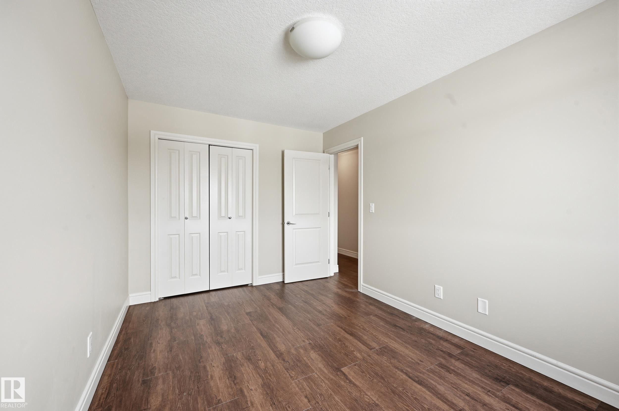 Unfurnished bedroom featuring dark wood finished floors, a textured ceiling, and a closet - 1351 Cunningham Drive, Edmonton, AB - Indoor Photo Showing Other Room