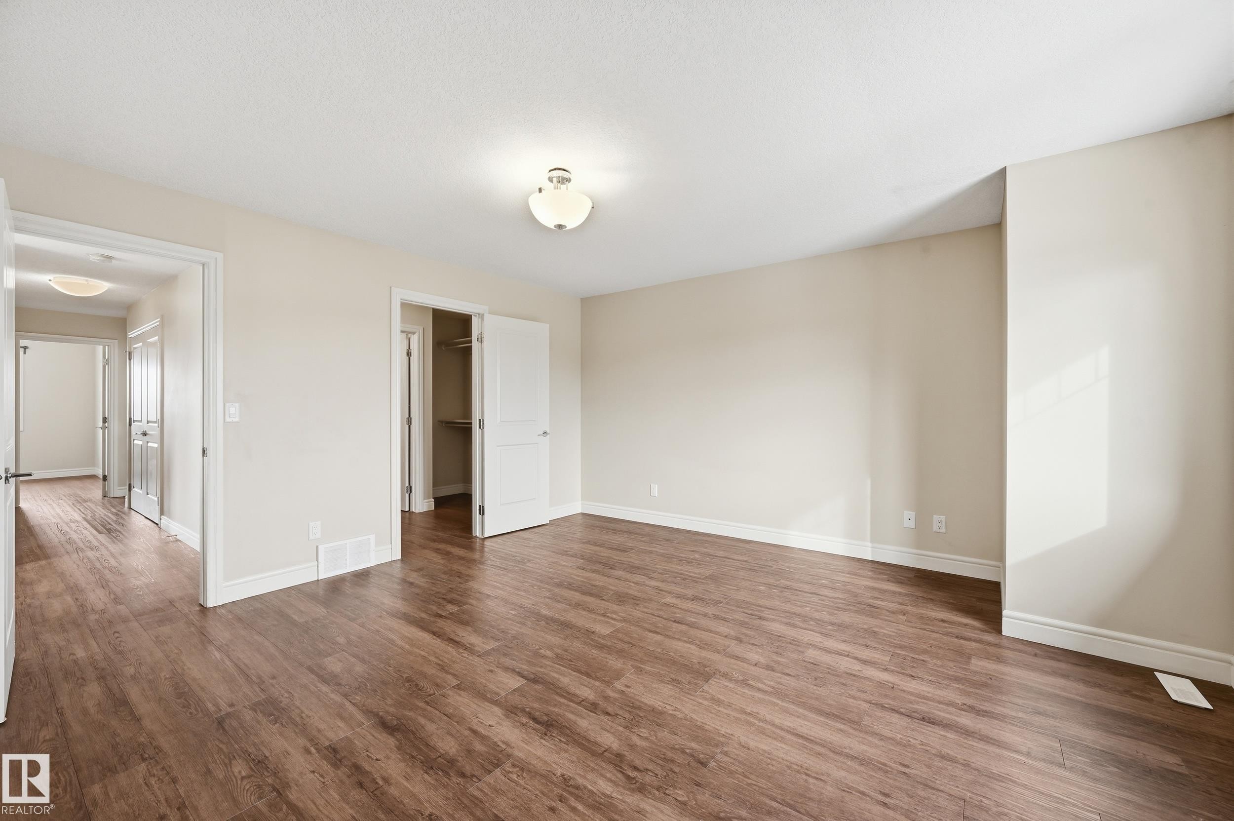Unfurnished bedroom featuring a walk in closet and dark wood-style floors - 1351 Cunningham Drive, Edmonton, AB - Indoor Photo Showing Other Room