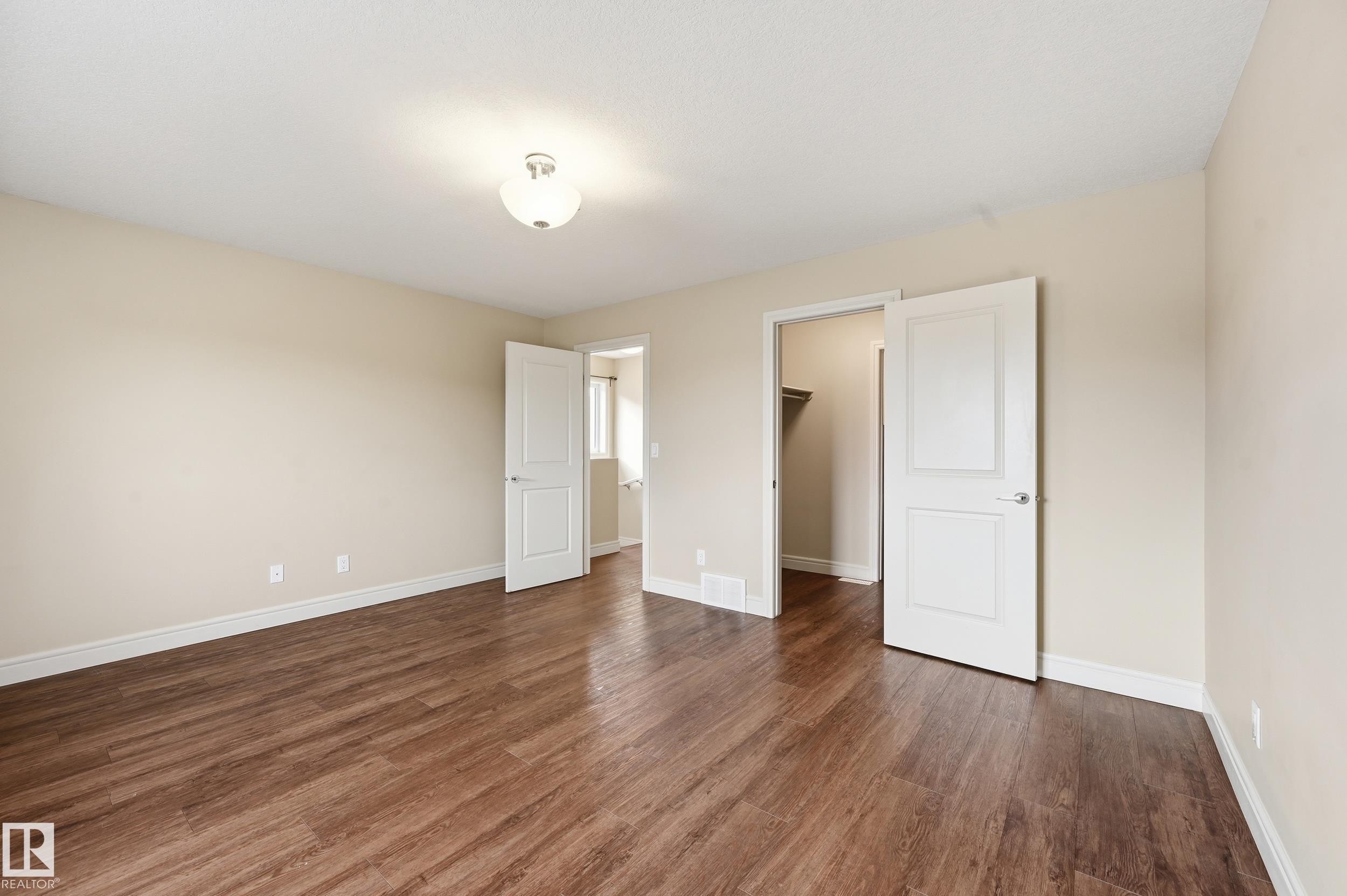 Unfurnished bedroom with a spacious closet and dark wood-style flooring - 1351 Cunningham Drive, Edmonton, AB - Indoor Photo Showing Other Room