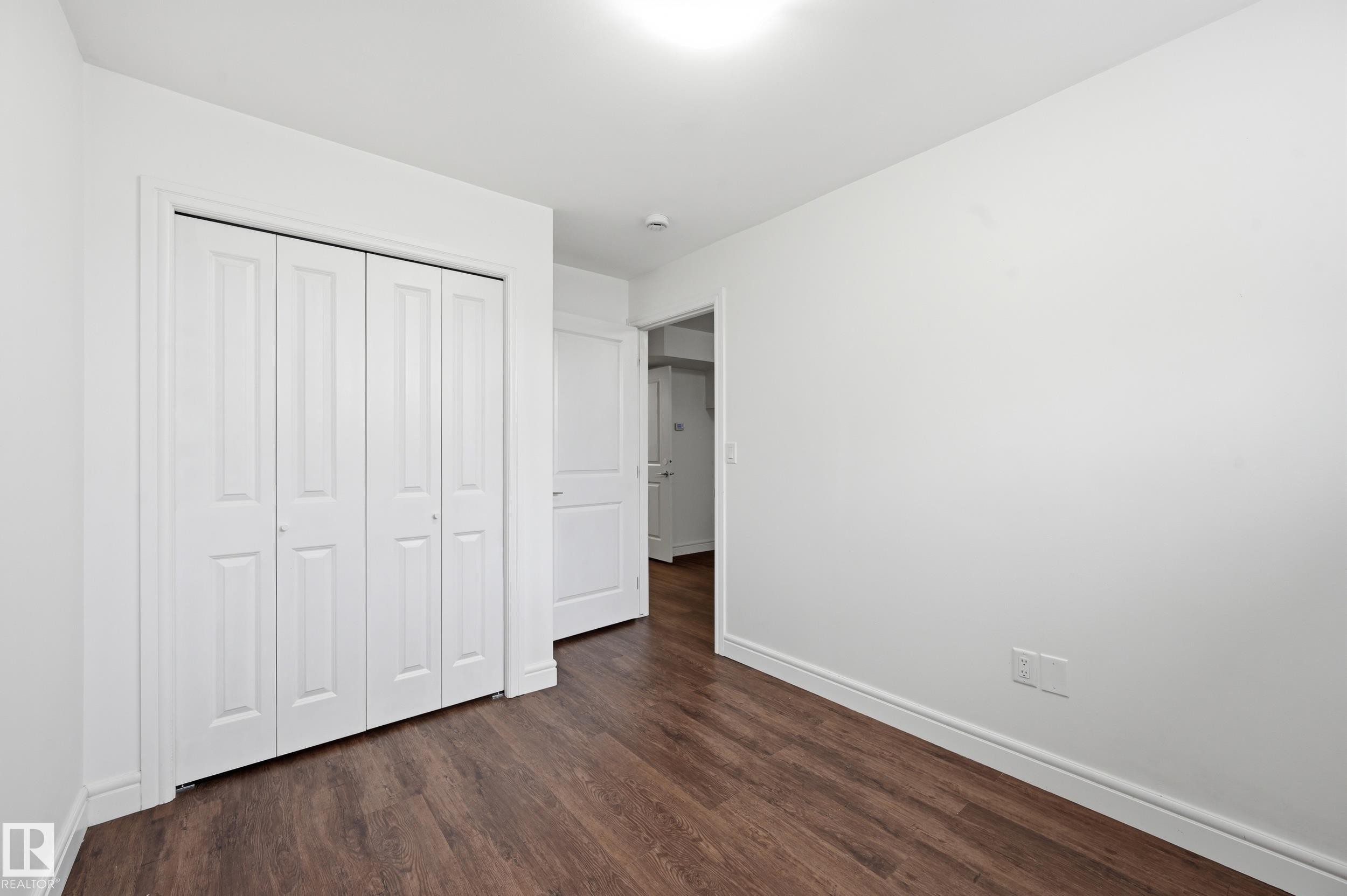 Unfurnished bedroom with dark wood-style flooring and a closet - 1351 Cunningham Drive, Edmonton, AB - Indoor