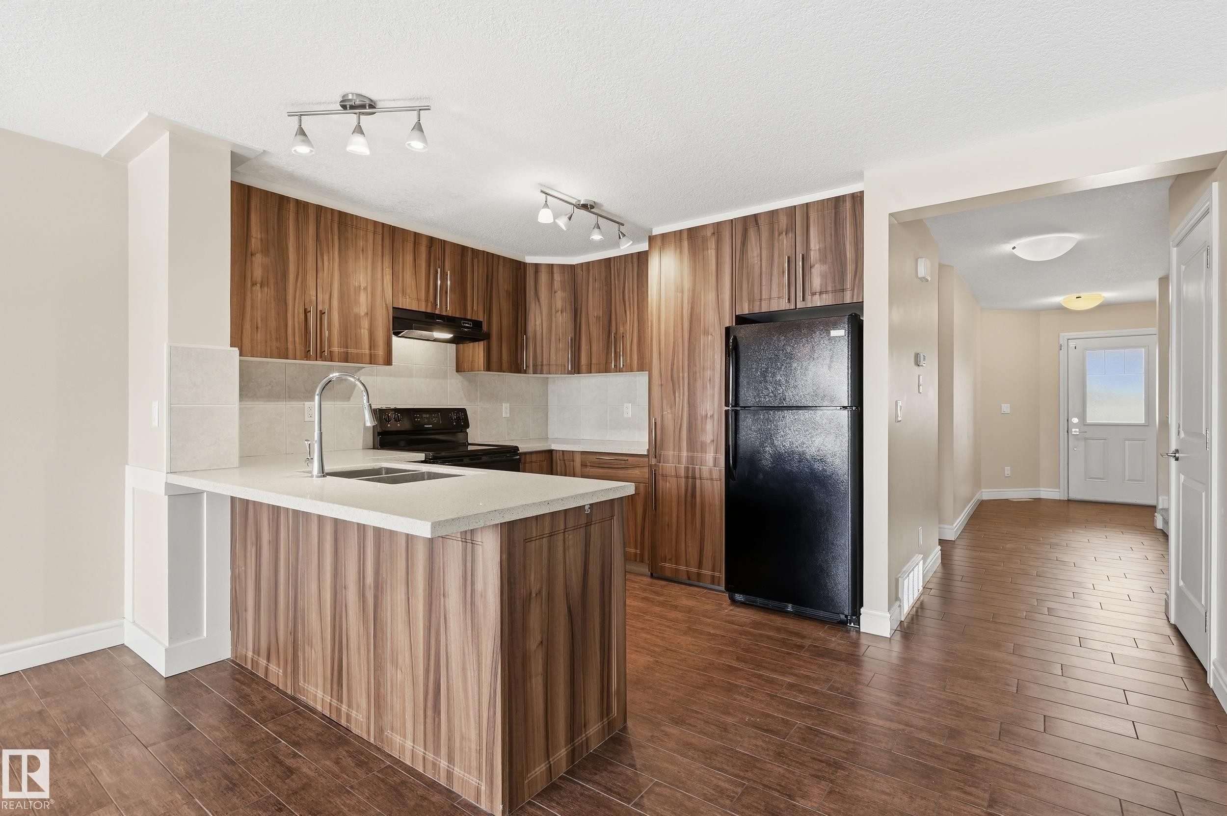 Kitchen featuring wood finish cabinets, black appliances, dark wood-style floors, a peninsula, and a textured ceiling - 1351 Cunningham Drive, Edmonton, AB - Indoor Photo Showing Kitchen