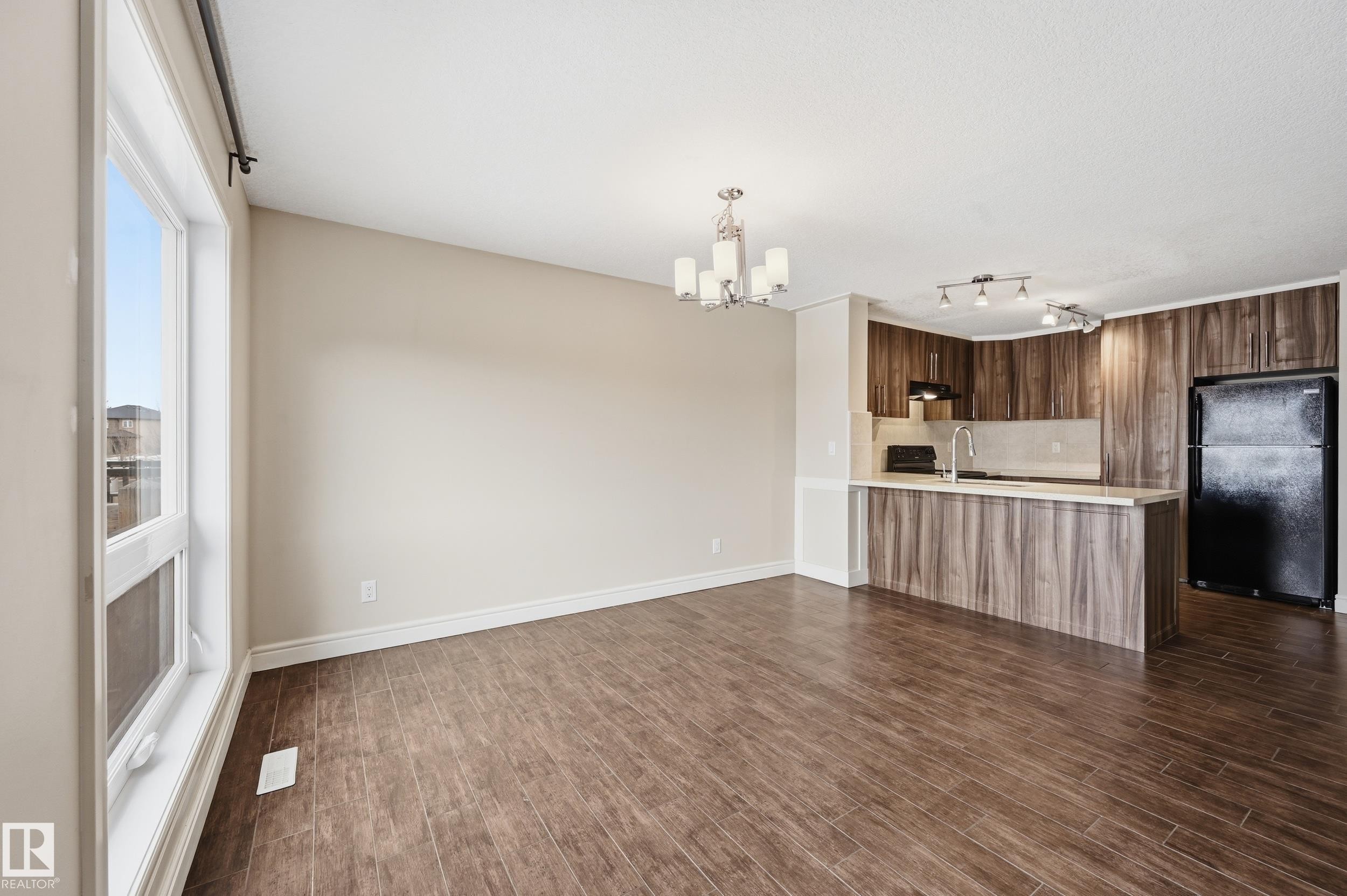 Unfurnished living room featuring dark wood-type flooring and a chandelier - 1351 Cunningham Drive, Edmonton, AB - Indoor Photo Showing Kitchen