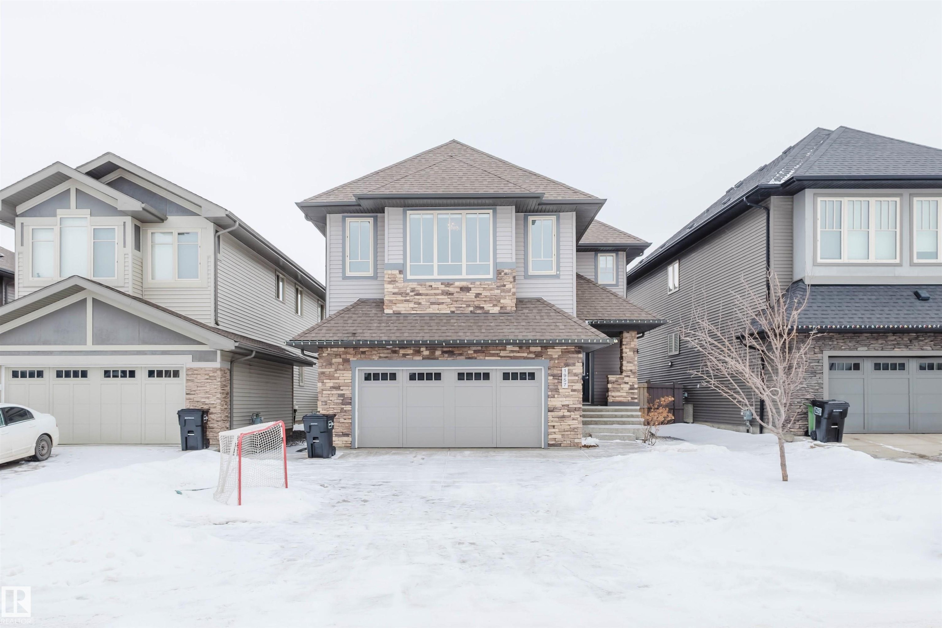 View of front facade with roof with shingles, stone siding, and an attached garage - 1957 Ainslie Link, Edmonton, AB - Outdoor With Facade