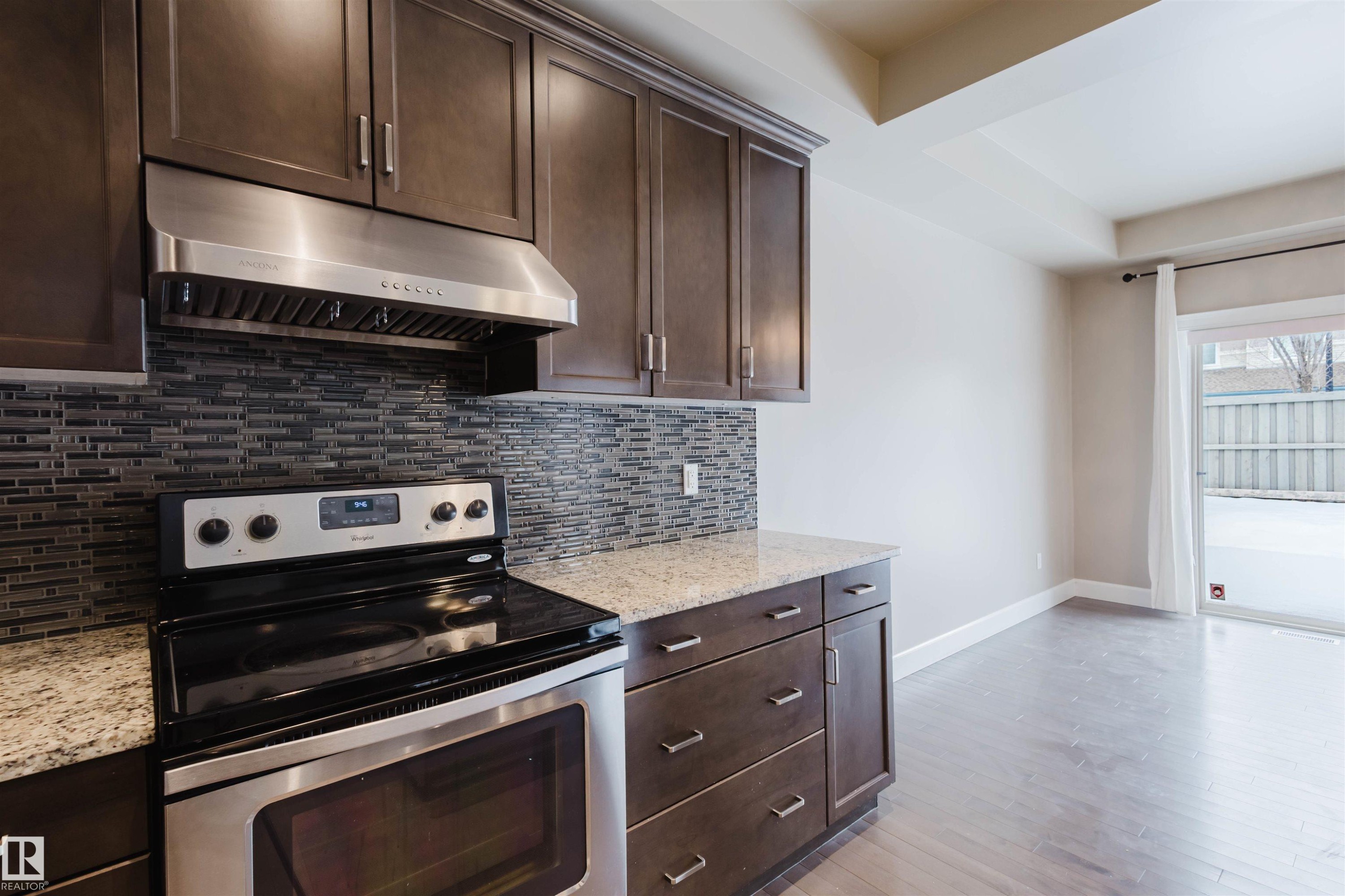 Kitchen with electric stove, dark wood finish cabinets, and light stone countertops - 1957 Ainslie Link, Edmonton, AB - Indoor Photo Showing Kitchen