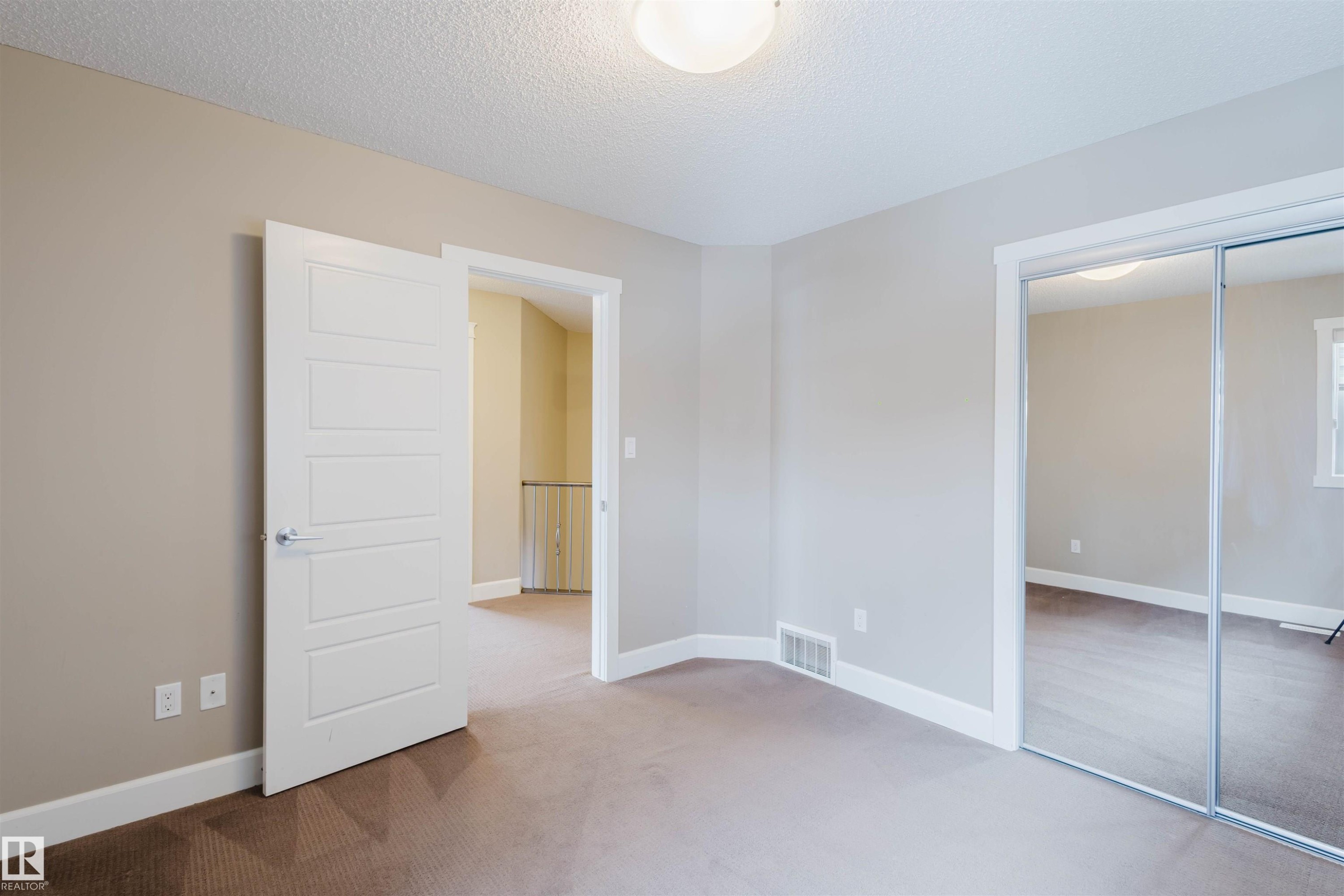 Unfurnished bedroom with light colored carpet, a textured ceiling, and a closet - 1957 Ainslie Link, Edmonton, AB - Indoor Photo Showing Other Room