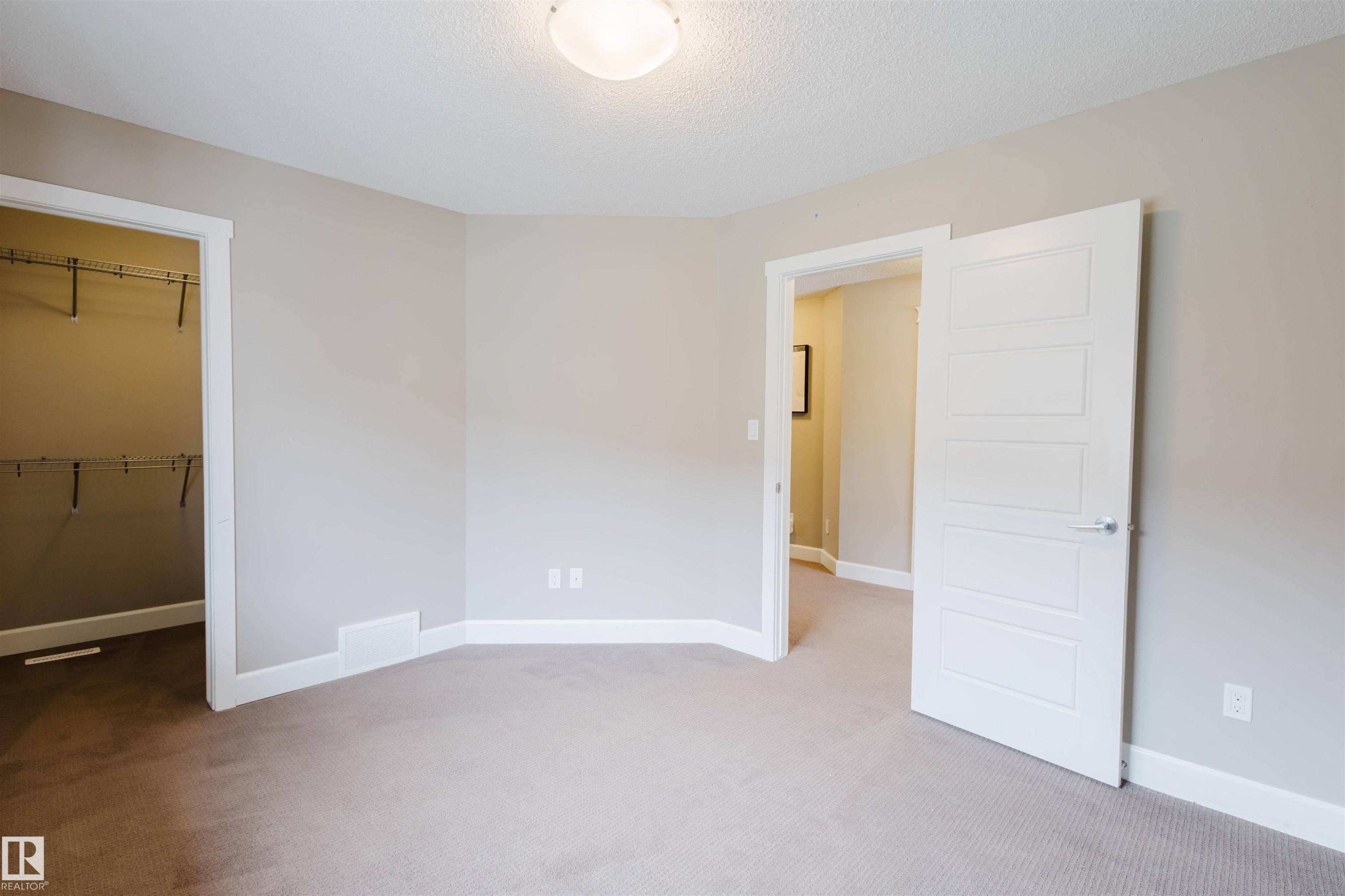 Unfurnished bedroom with light carpet, a walk in closet, and a textured ceiling - 1957 Ainslie Link, Edmonton, AB - Indoor Photo Showing Other Room