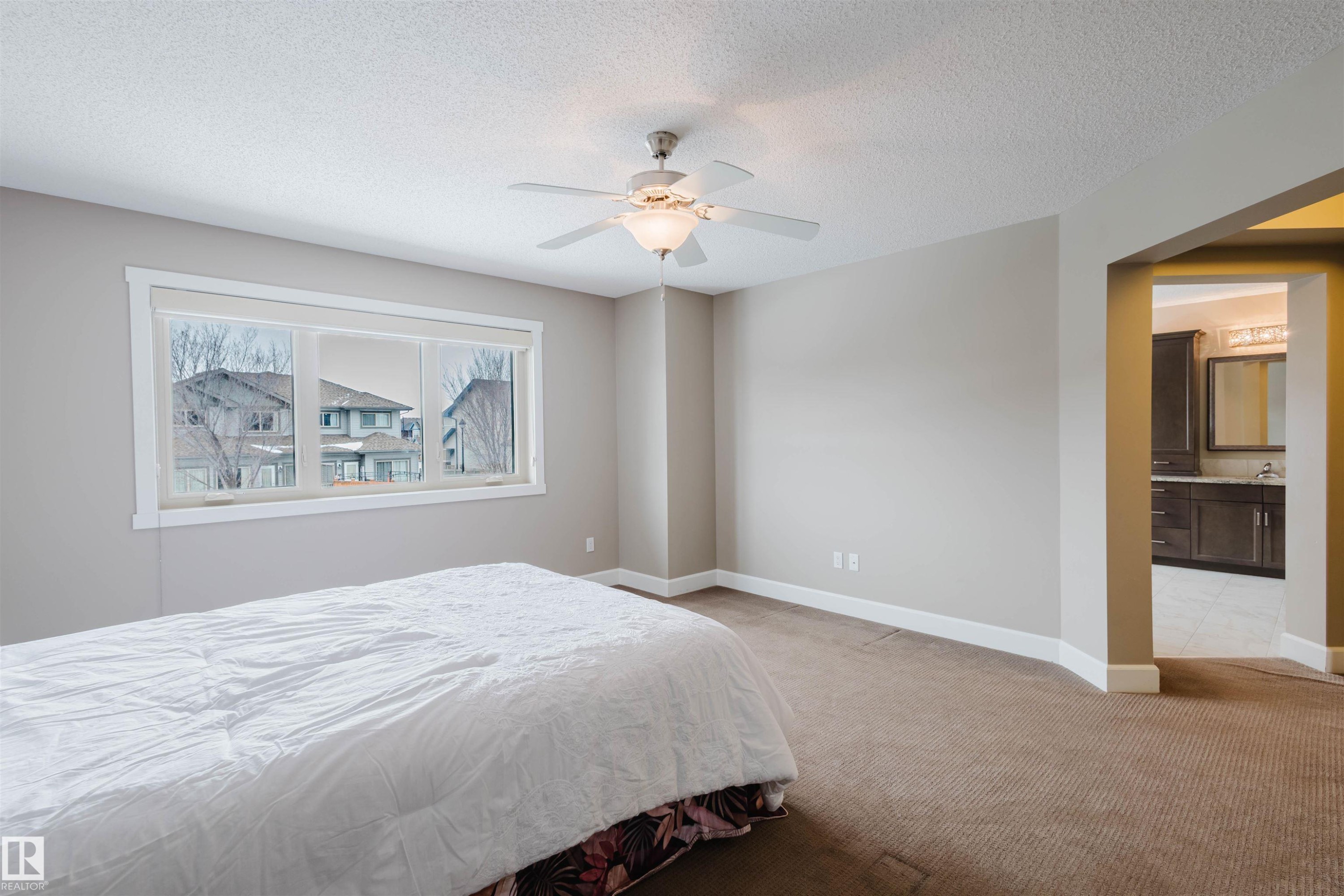 Bedroom featuring light carpet, ceiling fan, a textured ceiling, and ensuite bathroom - 1957 Ainslie Link, Edmonton, AB - Indoor Photo Showing Bedroom