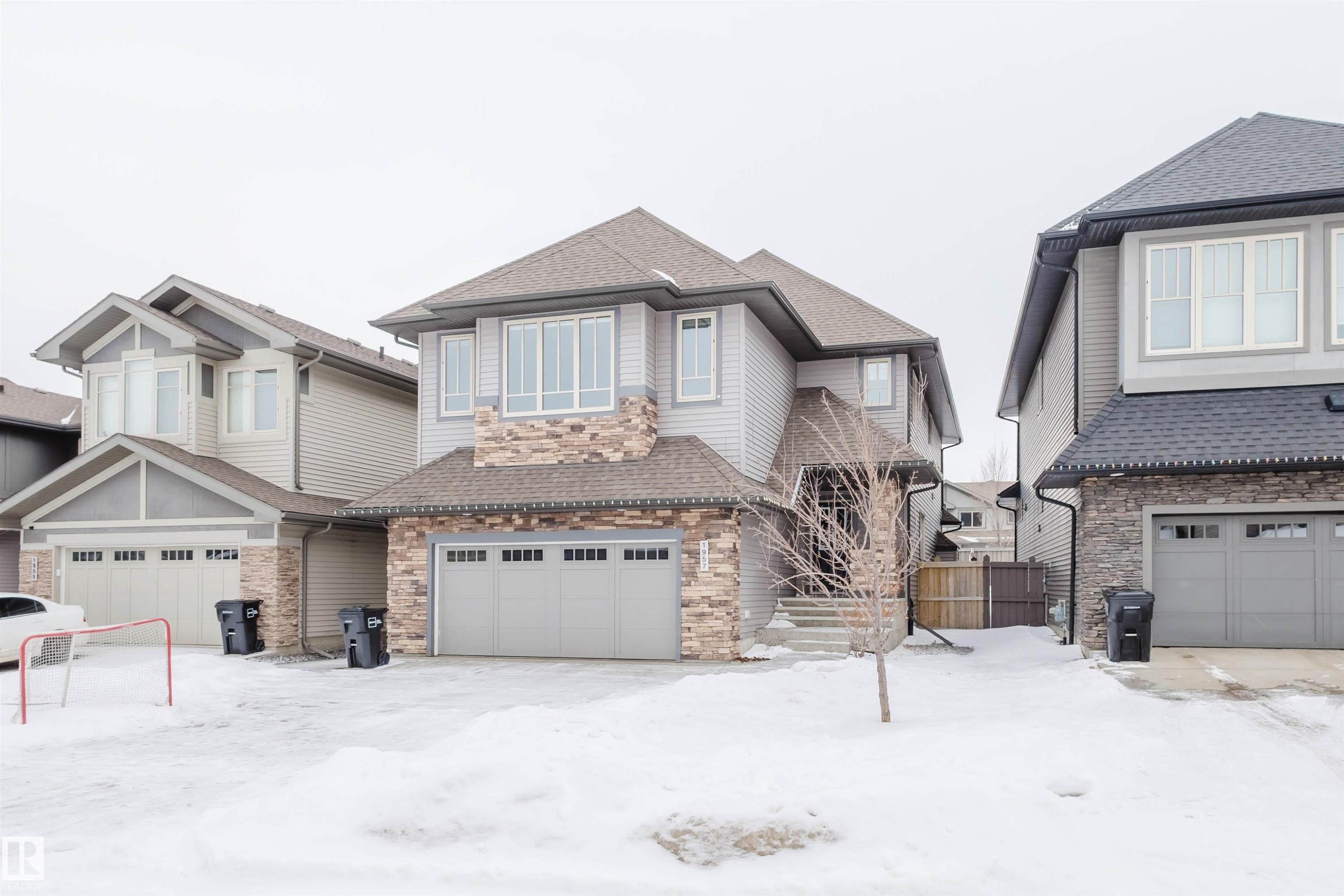 View of front of home with roof with shingles, stone siding, and a garage - 1957 Ainslie Link, Edmonton, AB - Outdoor With Facade