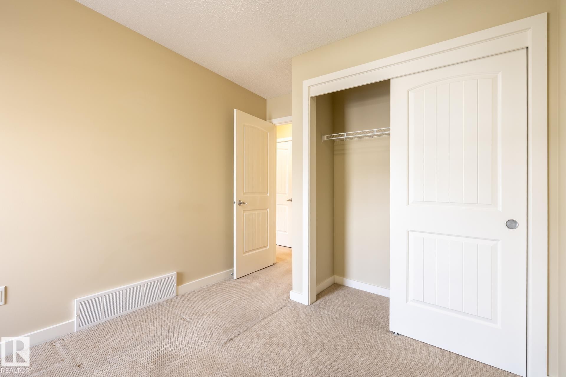 Unfurnished bedroom featuring light carpet, a closet, and a textured ceiling - 21 655 Watt Boulevard, Edmonton, AB - Indoor Photo Showing Other Room