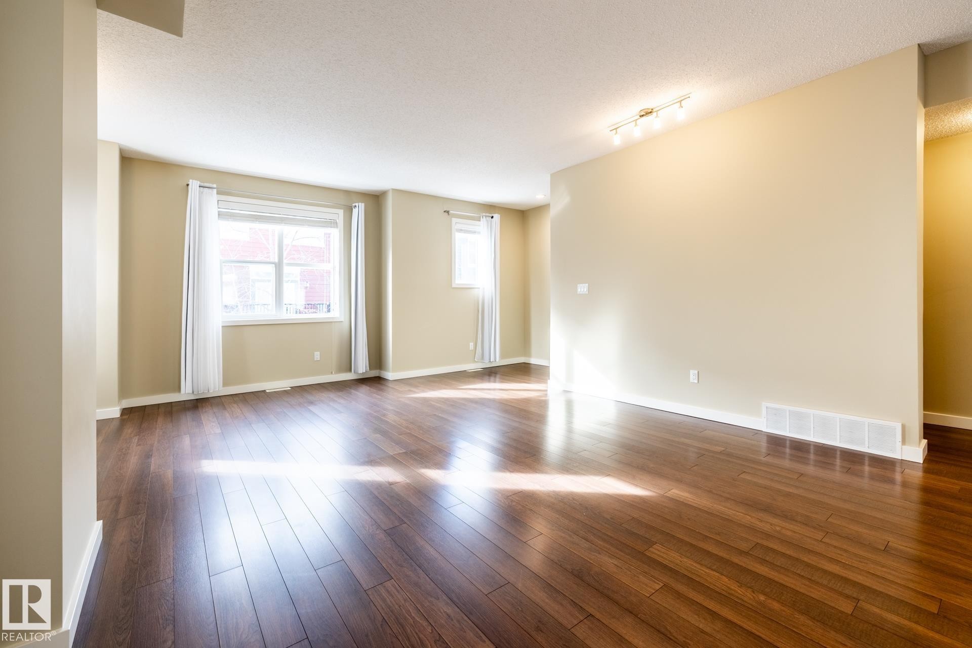 Empty room featuring dark wood finished floors, a textured ceiling, and rail lighting - 21 655 Watt Boulevard, Edmonton, AB - Indoor Photo Showing Other Room