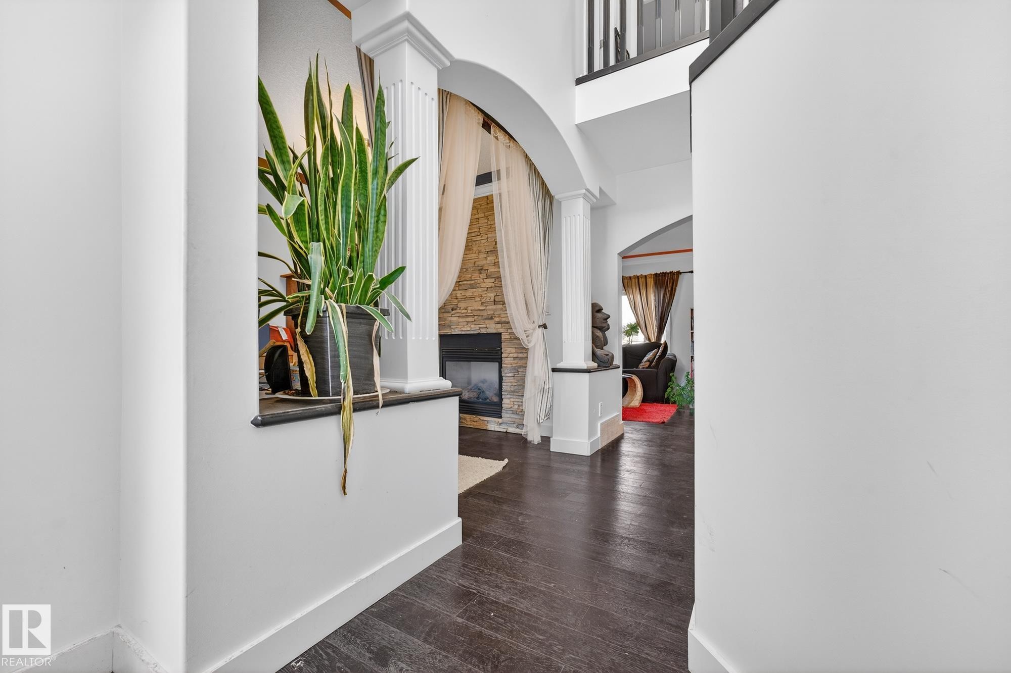 Hall featuring ornate columns, arched walkways, dark wood-style floors, and a high ceiling - 1660 Malone Way, Edmonton, AB - Indoor Photo Showing Other Room