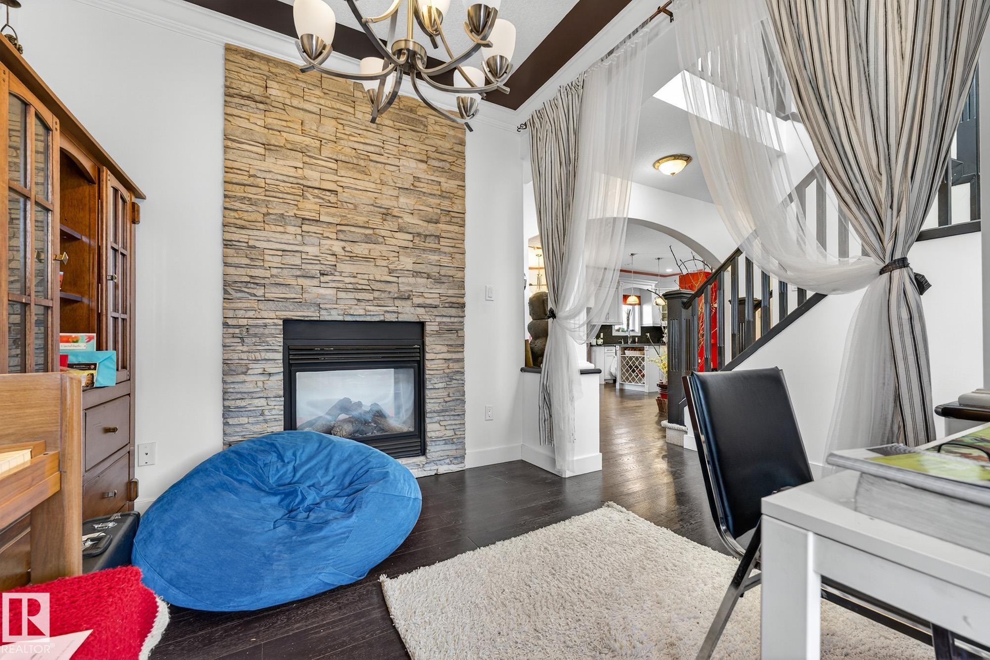 Office area with a fireplace, dark wood-type flooring, suspended lighting, and crown molding - 1660 Malone Way, Edmonton, AB - Indoor With Fireplace