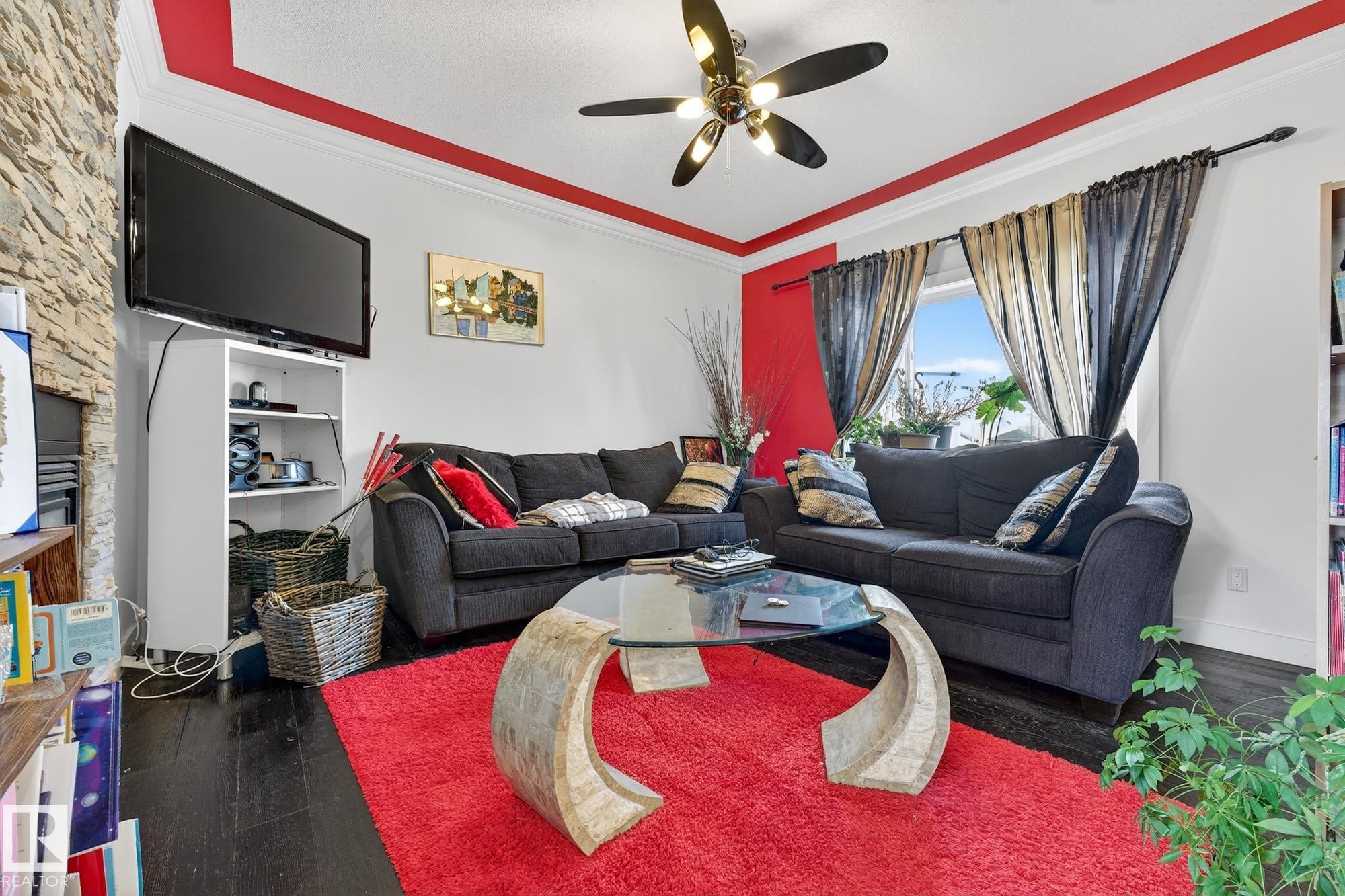 Living area with dark wood finished floors, ornamental molding, and a ceiling fan - 1660 Malone Way, Edmonton, AB - Indoor Photo Showing Living Room