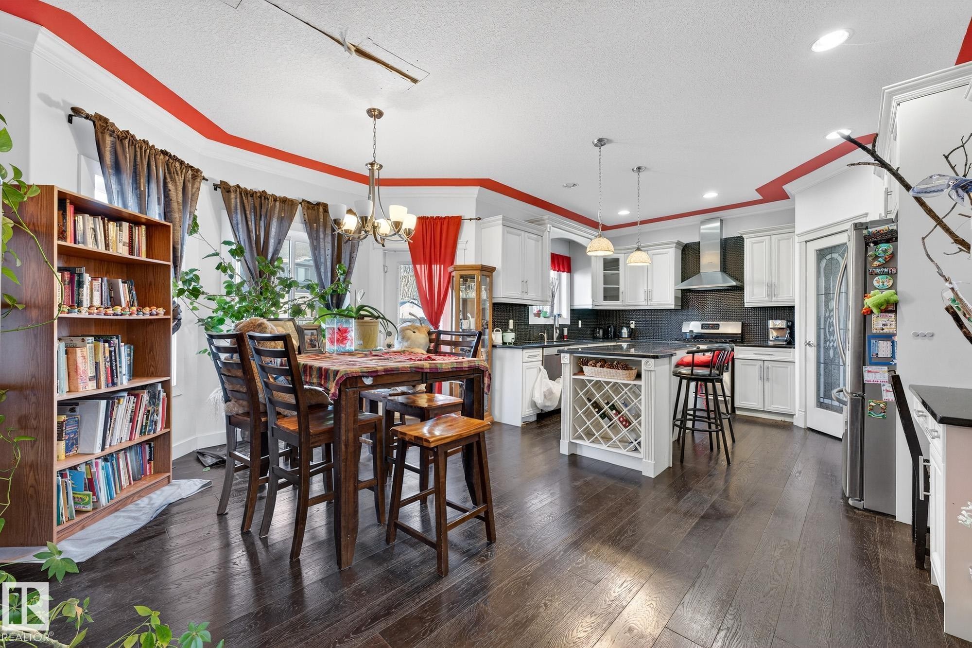 Dining area with a chandelier, dark wood finished floors, a textured ceiling, and ornamental molding - 1660 Malone Way, Edmonton, AB - Indoor