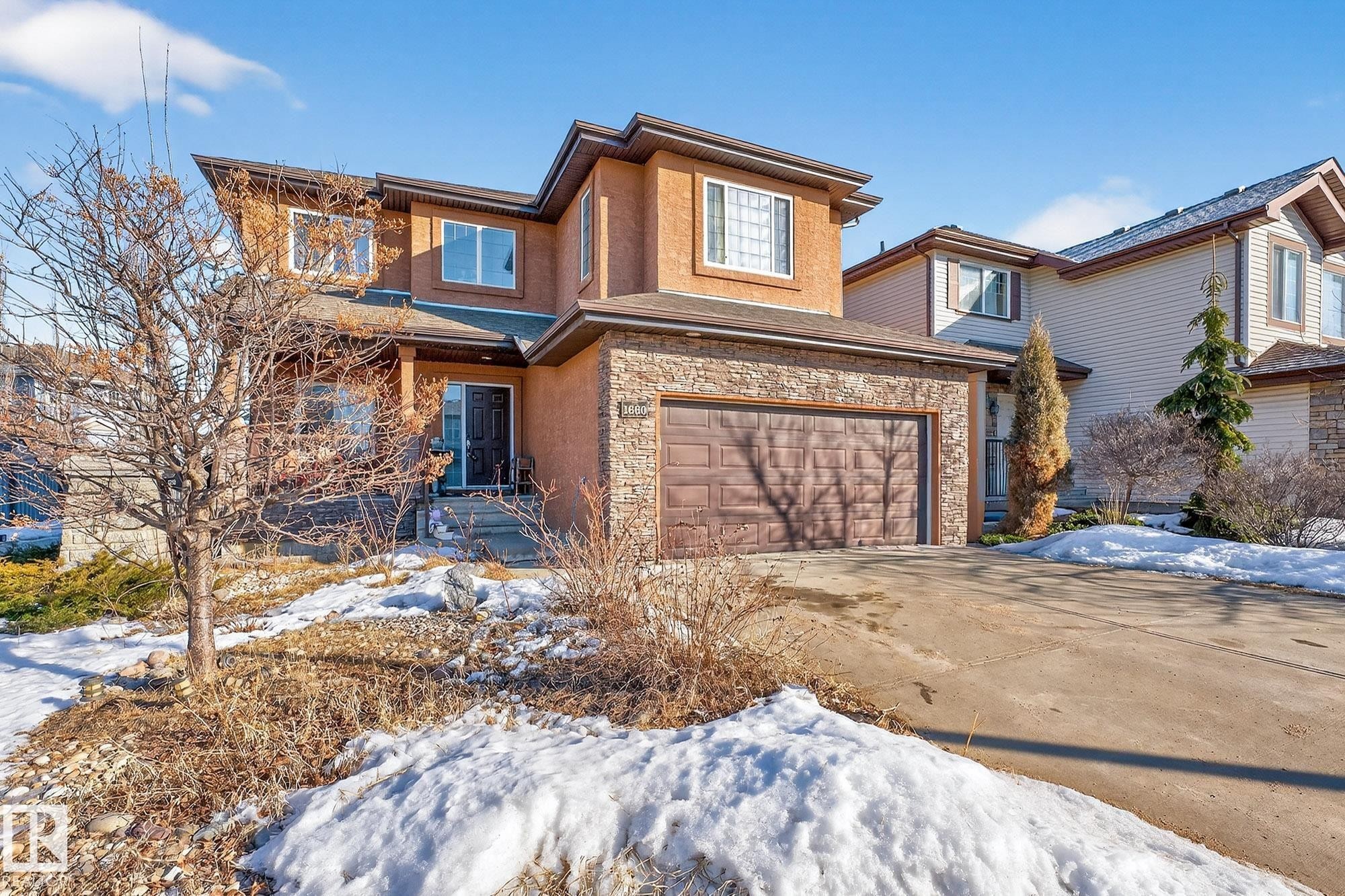 View of front of property with a garage, stone siding, driveway, and stucco siding - 1660 Malone Way, Edmonton, AB - Outdoor