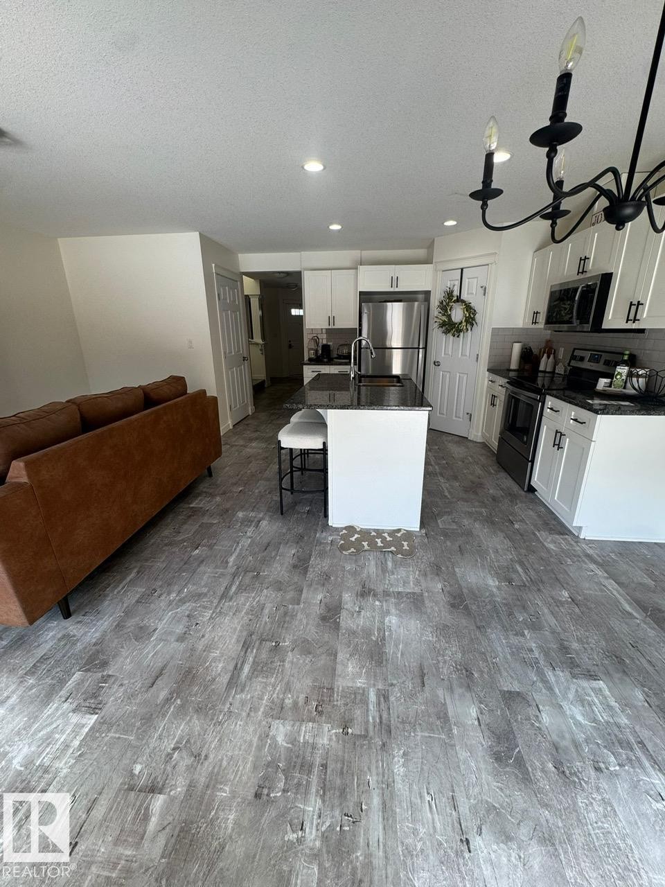 Kitchen with open floor plan, stainless steel appliances, an island with sink, a breakfast bar area, and dark stone counters - 17703 65 Street, Edmonton, AB - Indoor