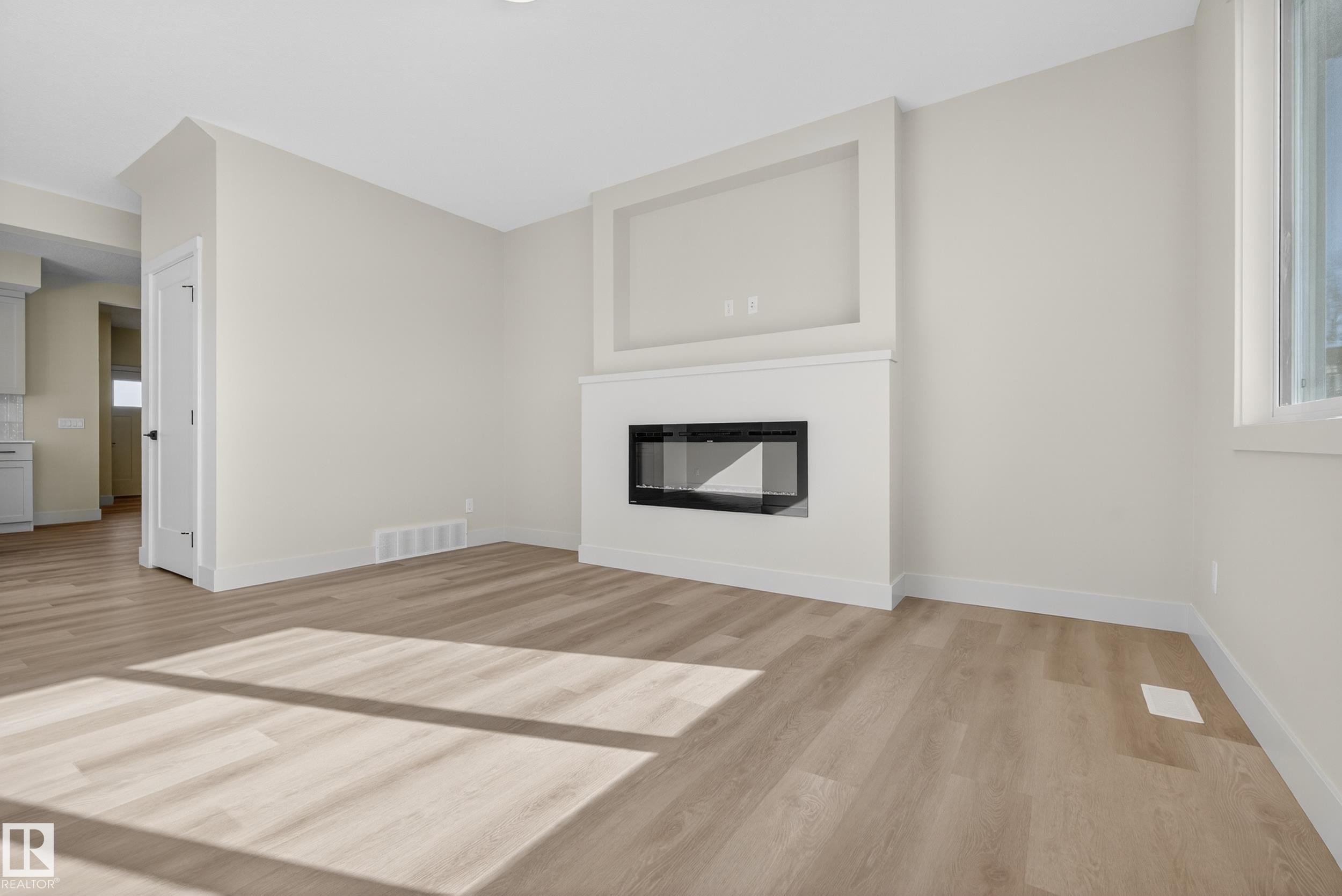 Unfurnished living room with light wood-type flooring and a glass covered fireplace - 22 Grayson Green, Stony Plain, AB - Indoor Photo Showing Living Room With Fireplace