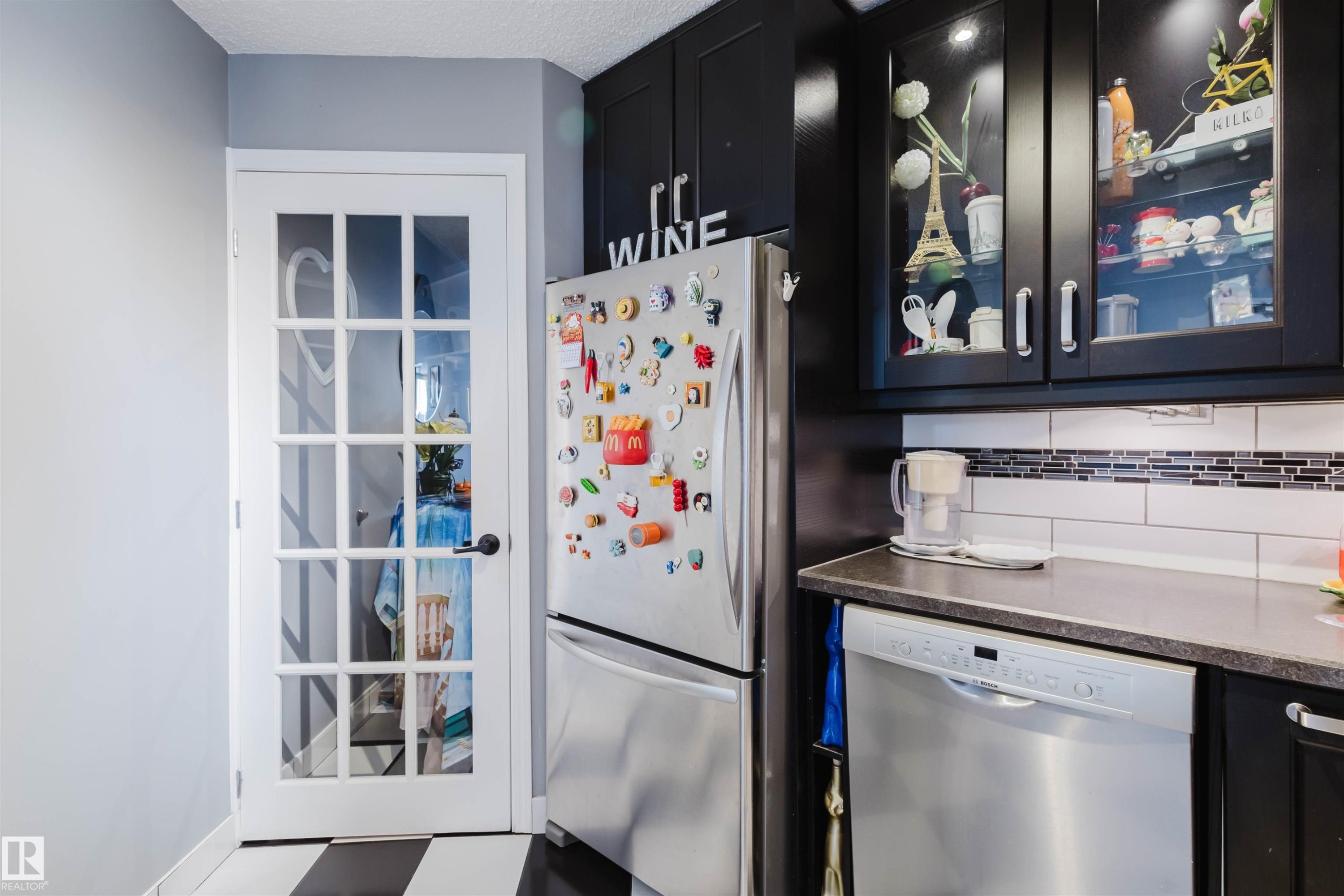 Kitchen featuring glass fronted cabinets, stainless steel appliances, dark cabinets, and dark stone counters - 1803 10149 Saskatchewan Drive, Edmonton, AB - Indoor