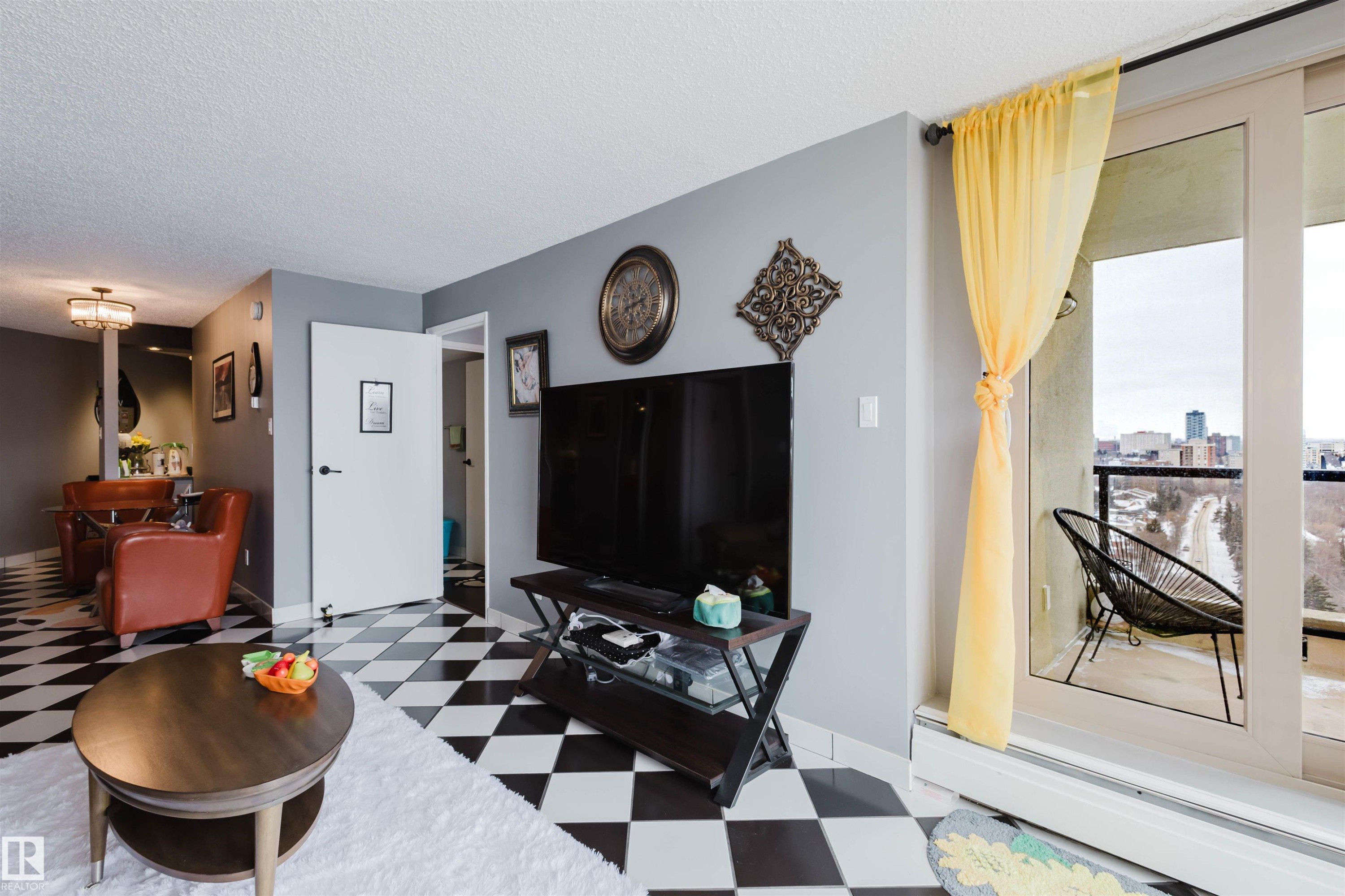 Living room with light flooring, a textured ceiling, and a baseboard heating unit - 1803 10149 Saskatchewan Drive, Edmonton, AB - Indoor