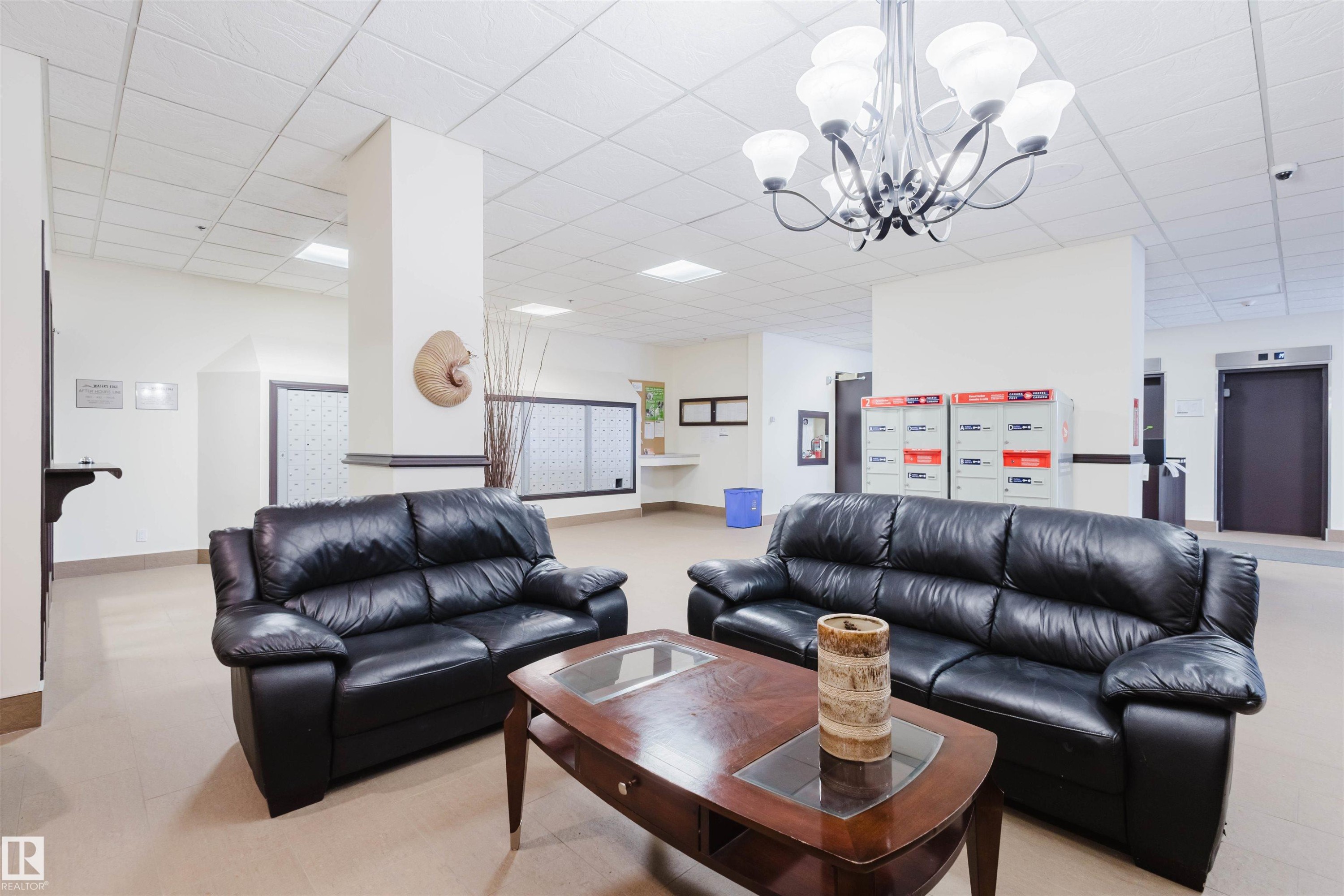 Living room with a paneled ceiling, elevator, and a chandelier - 1803 10149 Saskatchewan Drive, Edmonton, AB - Indoor Photo Showing Living Room