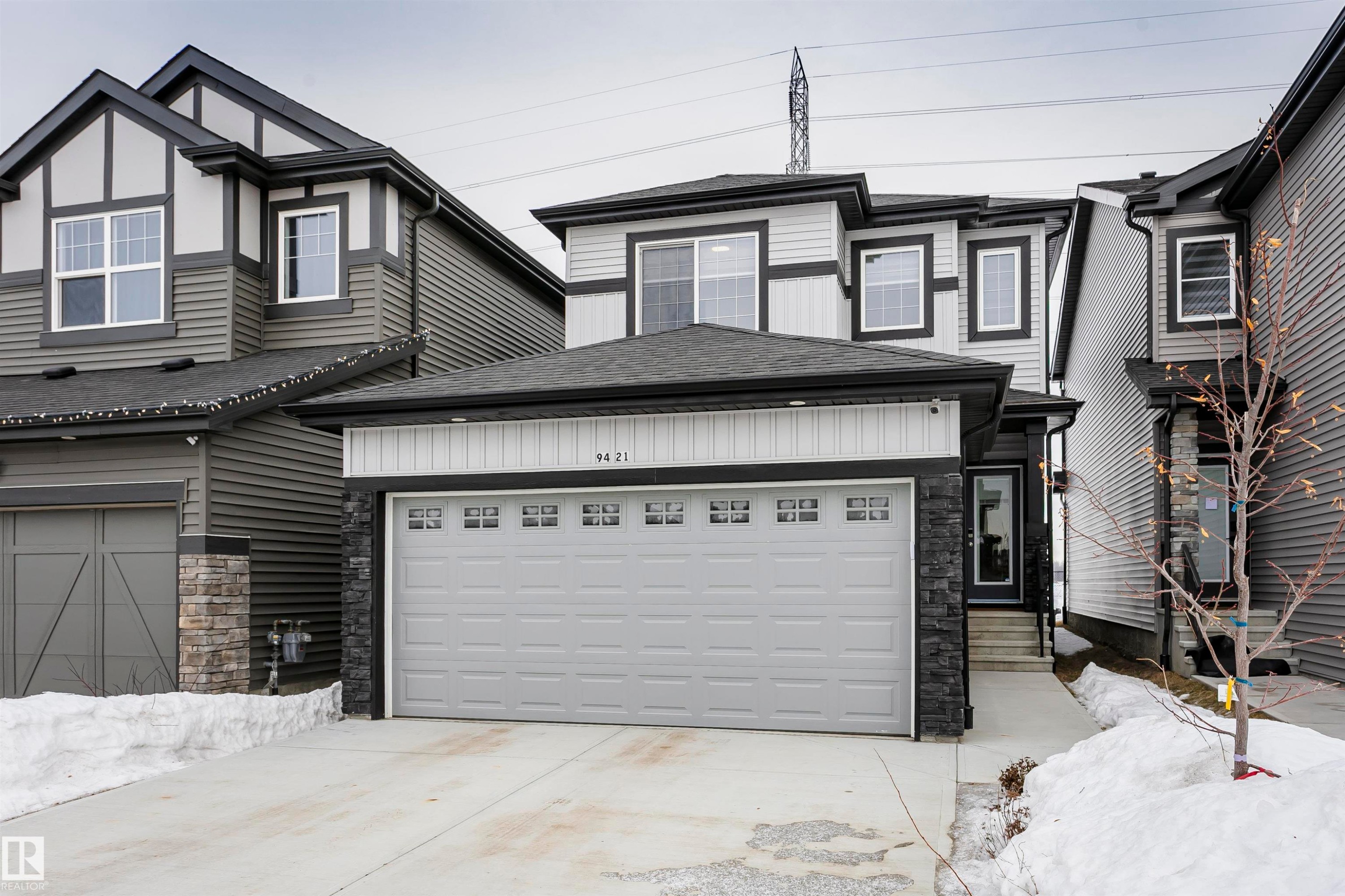 View of front of home featuring stone siding, a shingled roof, driveway, and a garage - 9421 Pear Crescent, Edmonton, AB - Outdoor