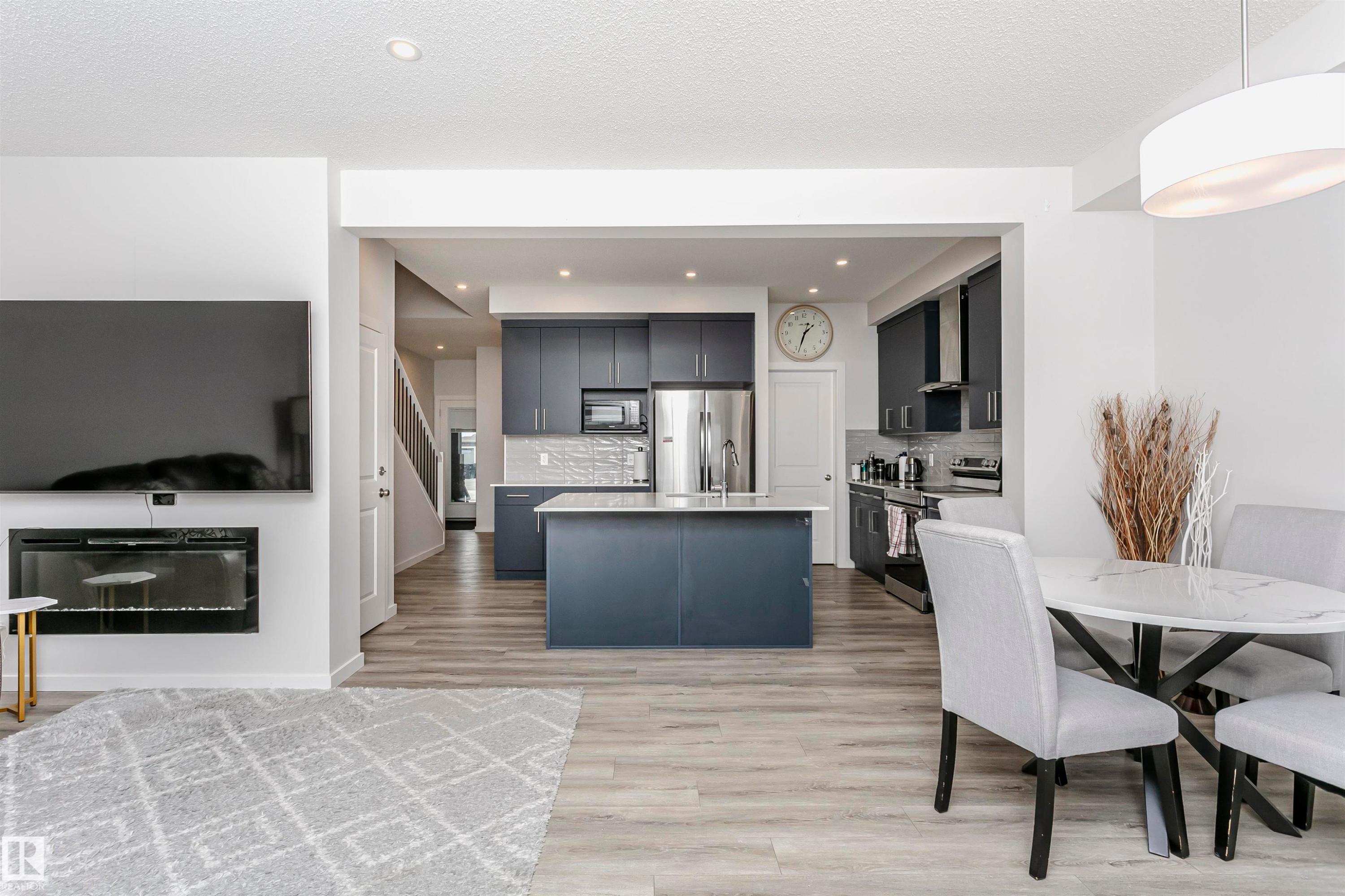 Kitchen featuring appliances with stainless steel finishes, a kitchen island, light wood-type flooring, backsplash, and decorative light fixtures - 9421 Pear Crescent, Edmonton, AB - Indoor