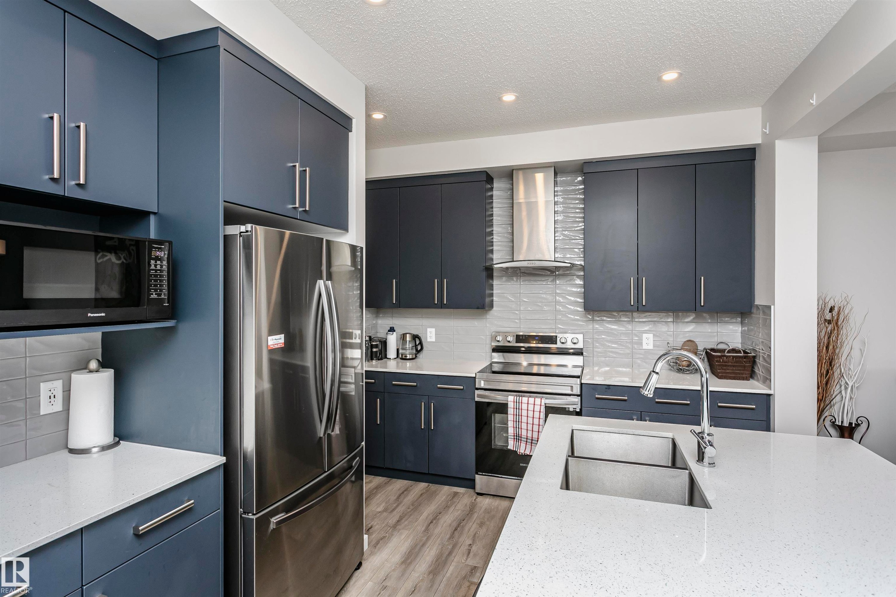 Kitchen with appliances with stainless steel finishes, backsplash, light stone counters, a textured ceiling, and recessed lighting - 9421 Pear Crescent, Edmonton, AB - Indoor Photo Showing Kitchen With Stainless Steel Kitchen With Upgraded Kitchen