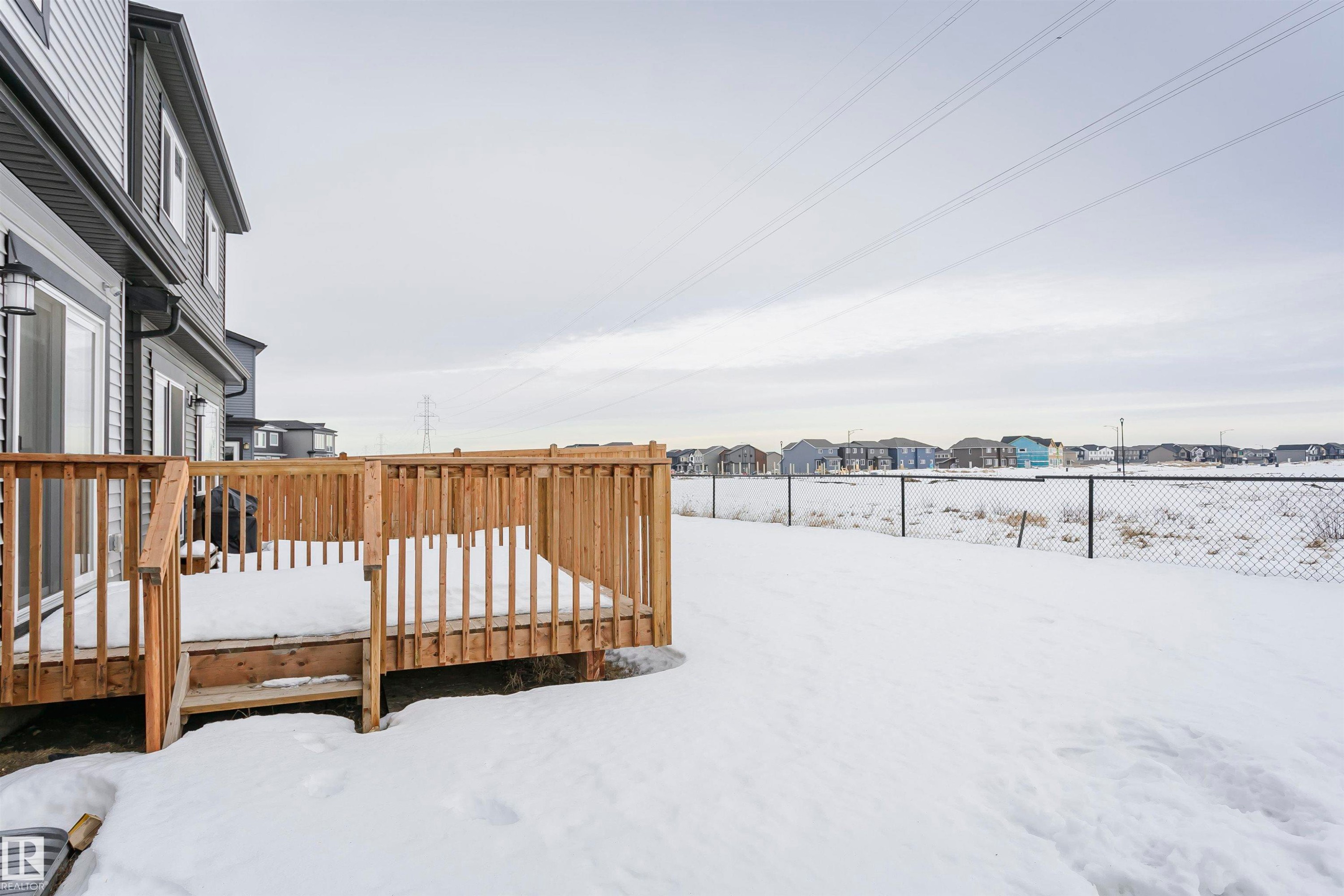 Yard layered in snow featuring a residential view and a wooden deck - 9421 Pear Crescent, Edmonton, AB - Outdoor