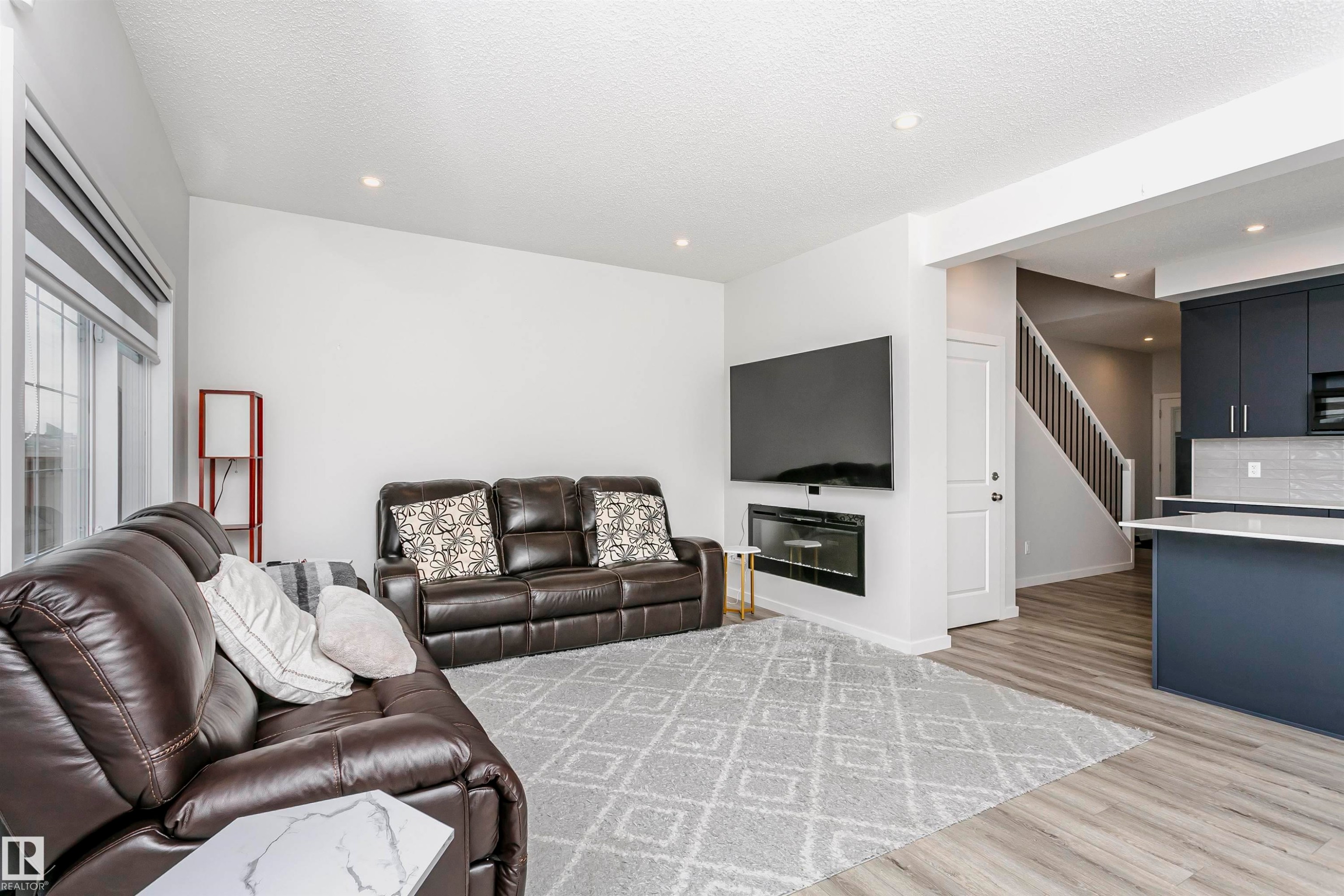 Living area with light wood-type flooring, recessed lighting, a textured ceiling, and stairway - 9421 Pear Crescent, Edmonton, AB - Indoor Photo Showing Living Room
