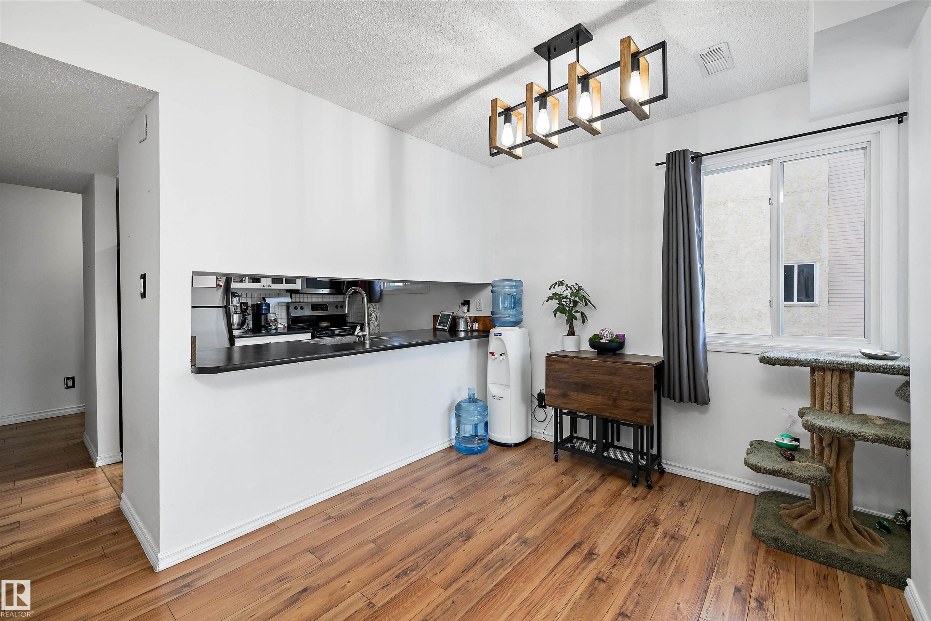 Kitchen featuring hardwood / wood-style floors, a textured ceiling, electric stove, dark countertops, and pendant lighting - 139 Lancaster Terrace, Edmonton, AB - Indoor Photo Showing Other Room