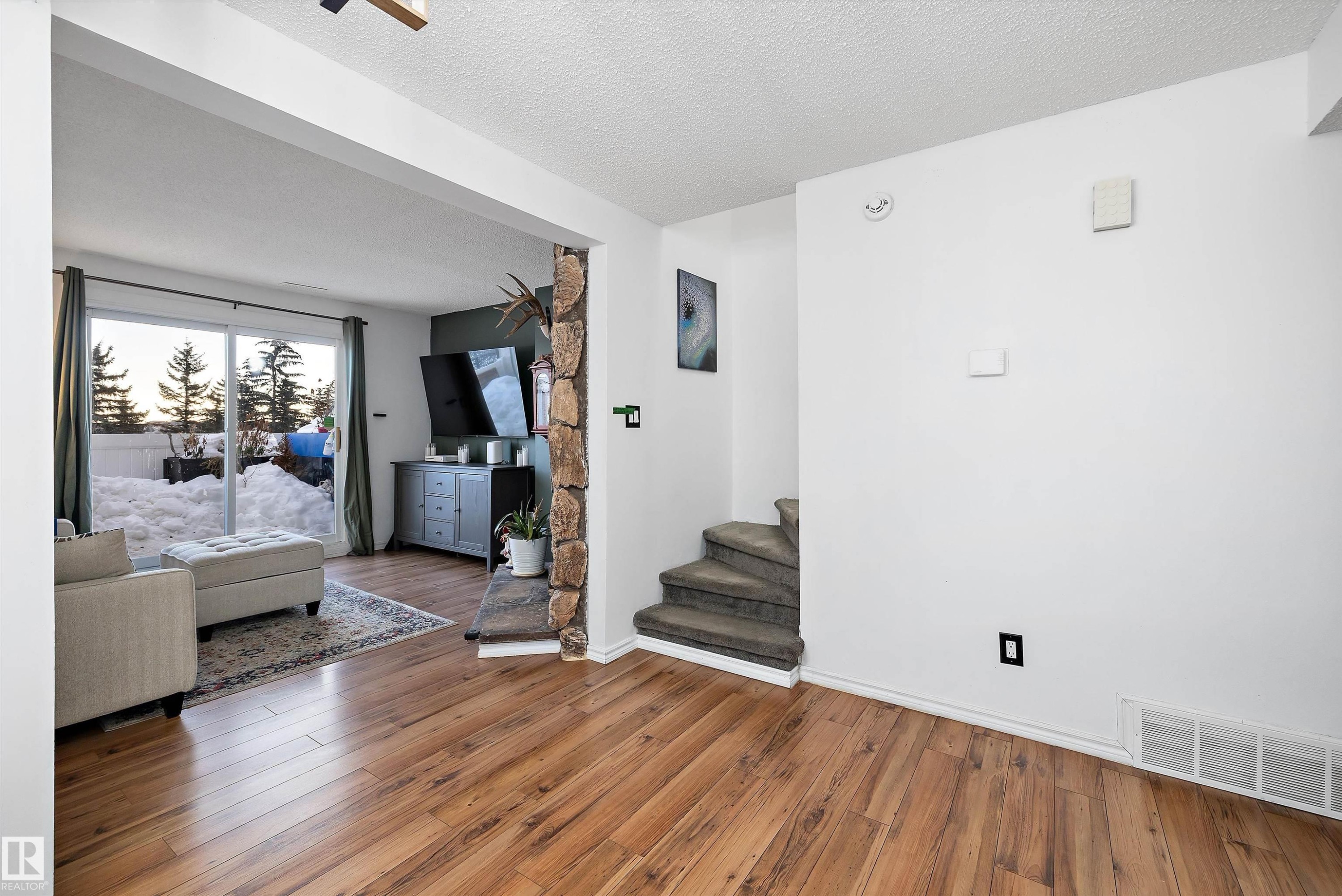 Unfurnished living room with a textured ceiling, hardwood / wood-style floors, and stairs - 139 Lancaster Terrace, Edmonton, AB - Indoor Photo Showing Living Room