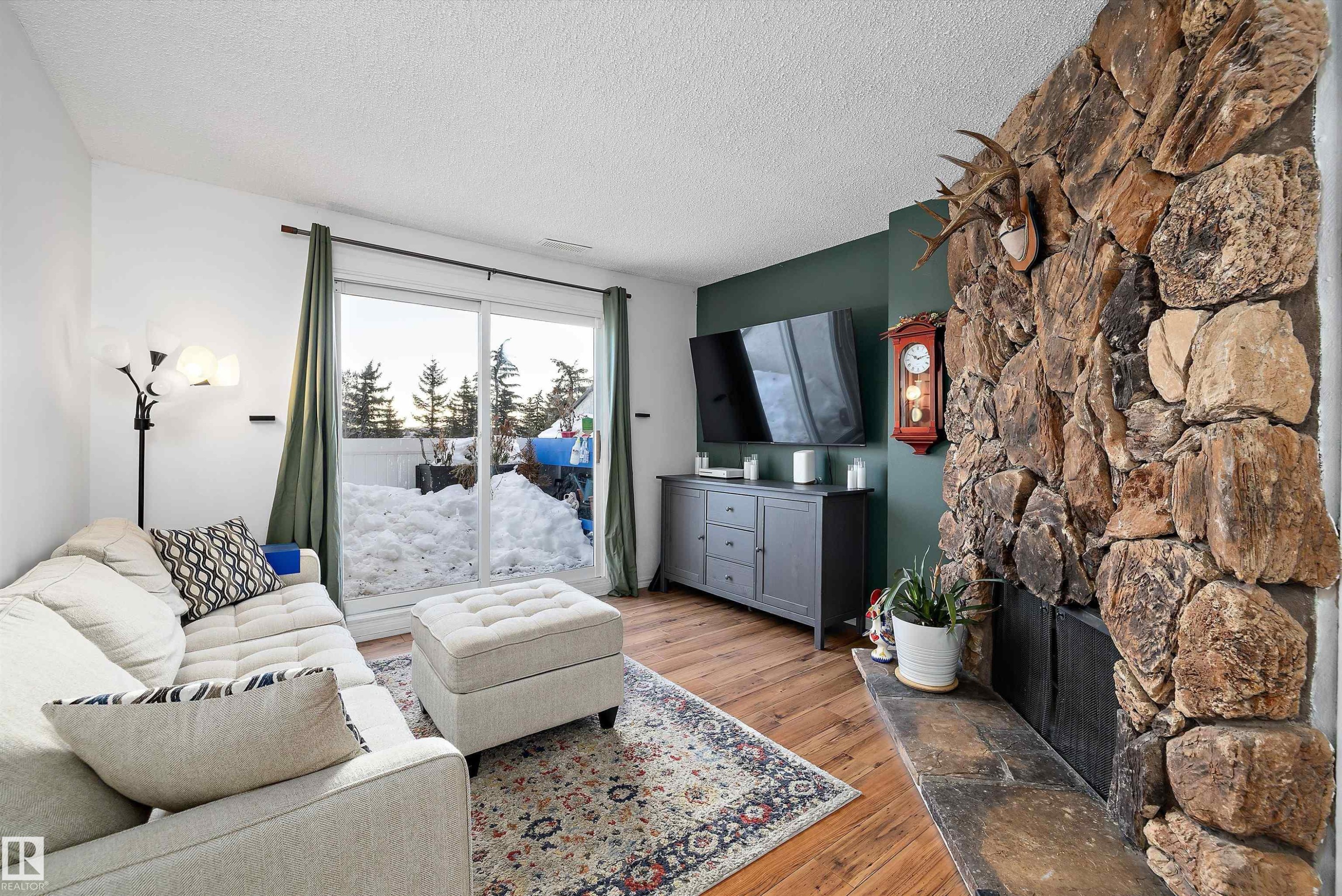 Living area featuring hardwood / wood-style flooring, a textured ceiling, and a stone fireplace - 139 Lancaster Terrace, Edmonton, AB - Indoor Photo Showing Living Room