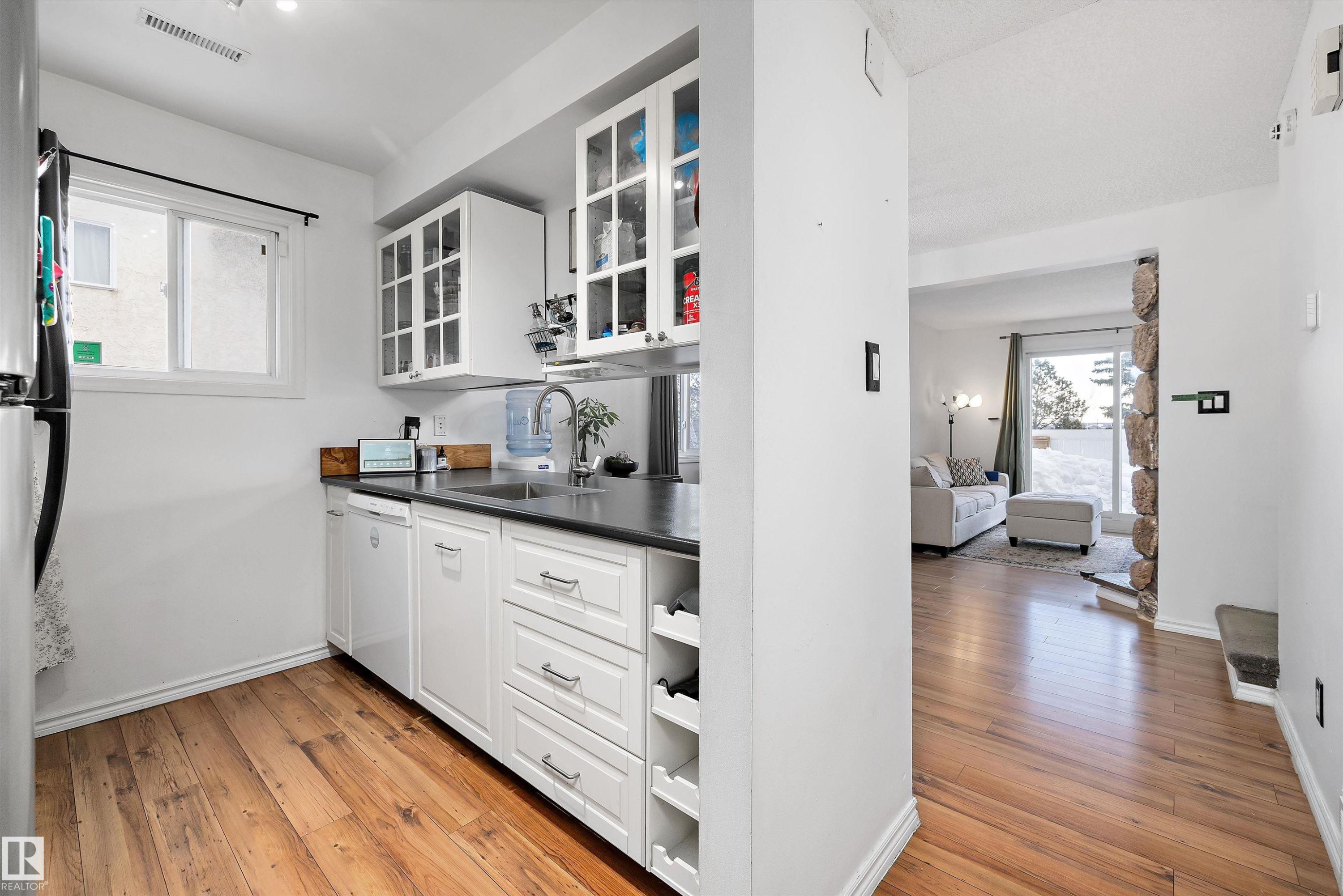 Kitchen with glass insert cabinets, white cabinetry, and light wood finished floors - 139 Lancaster Terrace, Edmonton, AB - Indoor