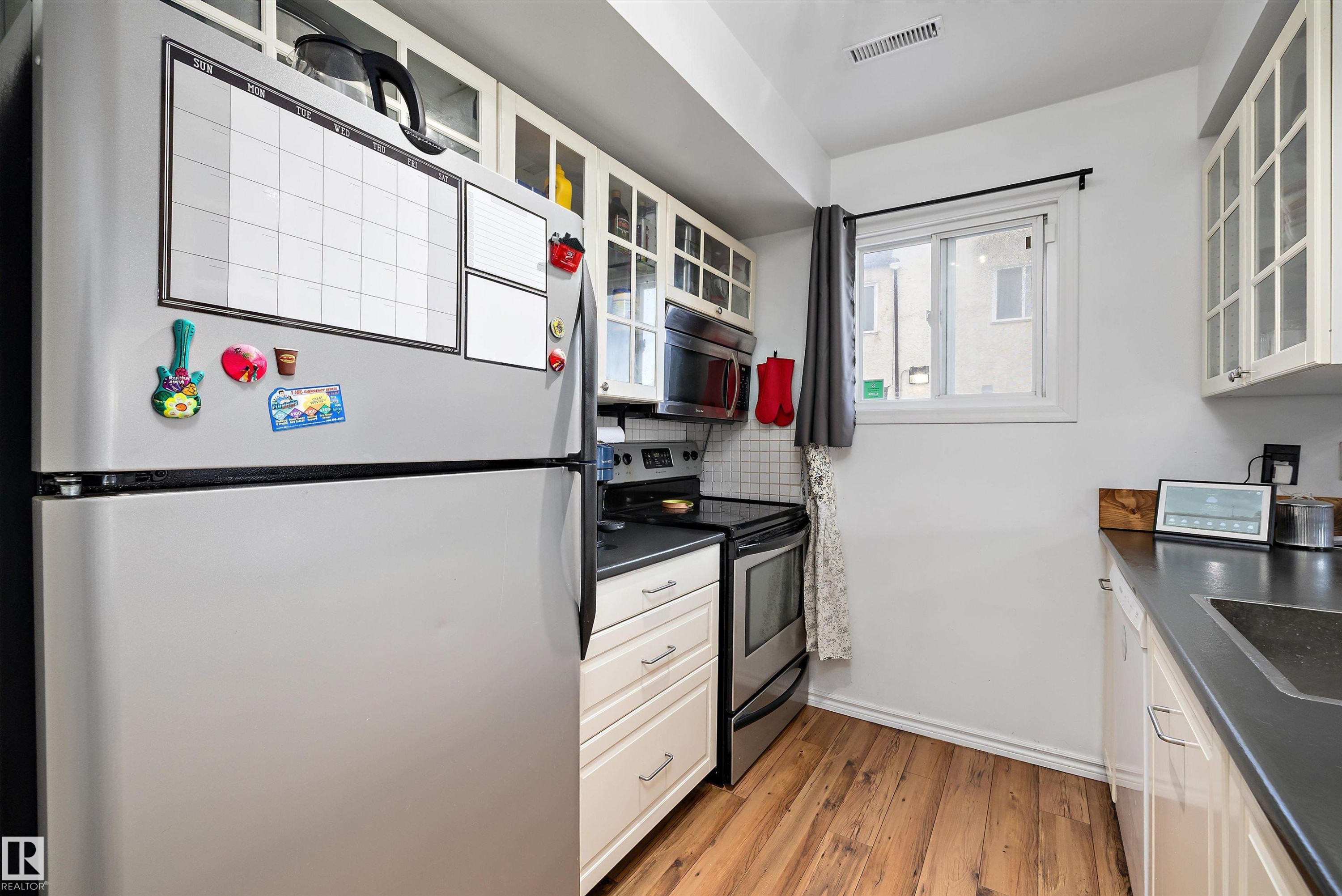 Kitchen with dark countertops, glass insert cabinets, appliances with stainless steel finishes, and white cabinets - 139 Lancaster Terrace, Edmonton, AB - Indoor Photo Showing Kitchen