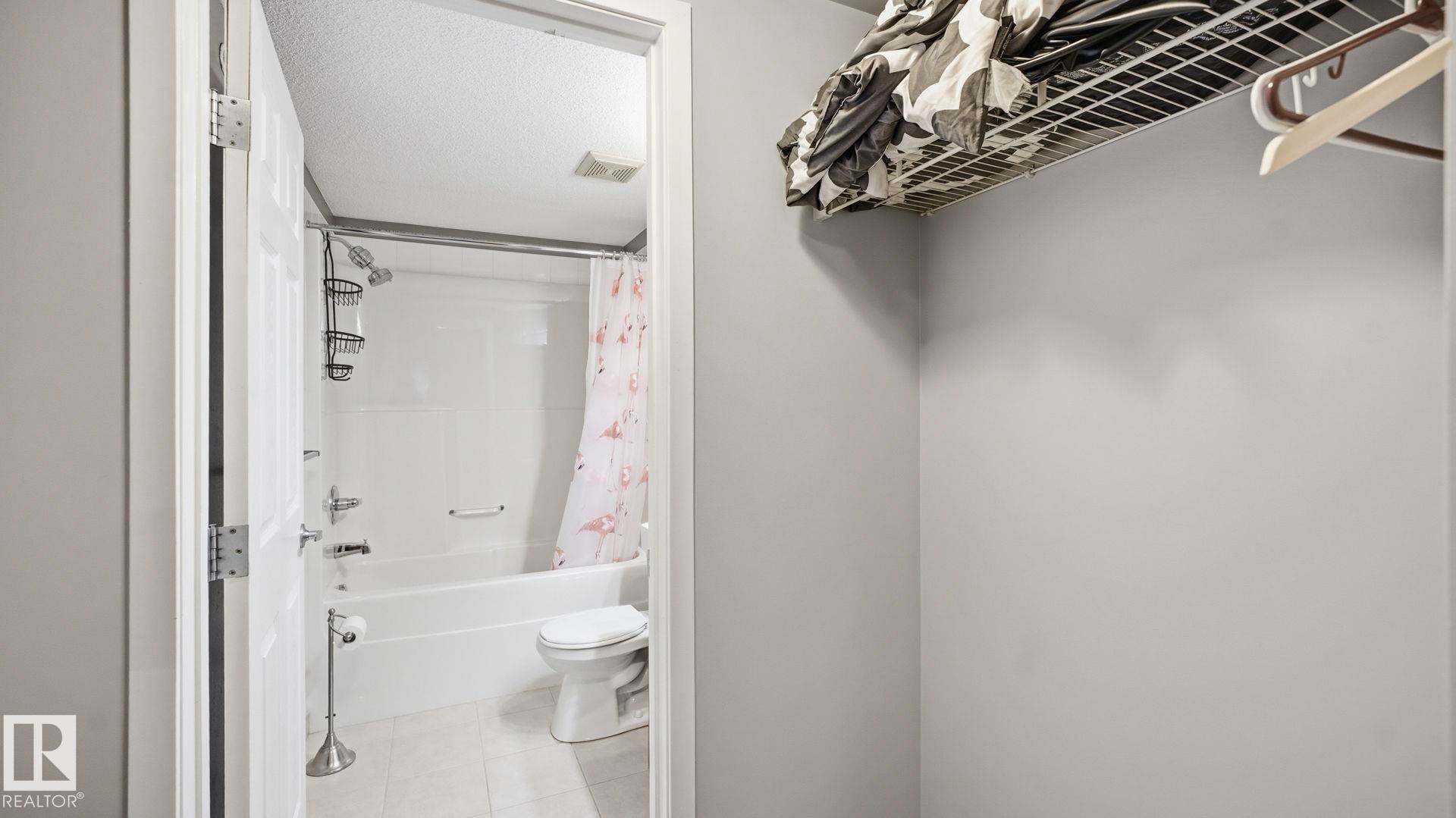 Full bathroom featuring shower / tub combo with curtain, a textured ceiling, and light tile patterned floors - 401 636 Mcallister Loop, Edmonton, AB - Indoor Photo Showing Bathroom