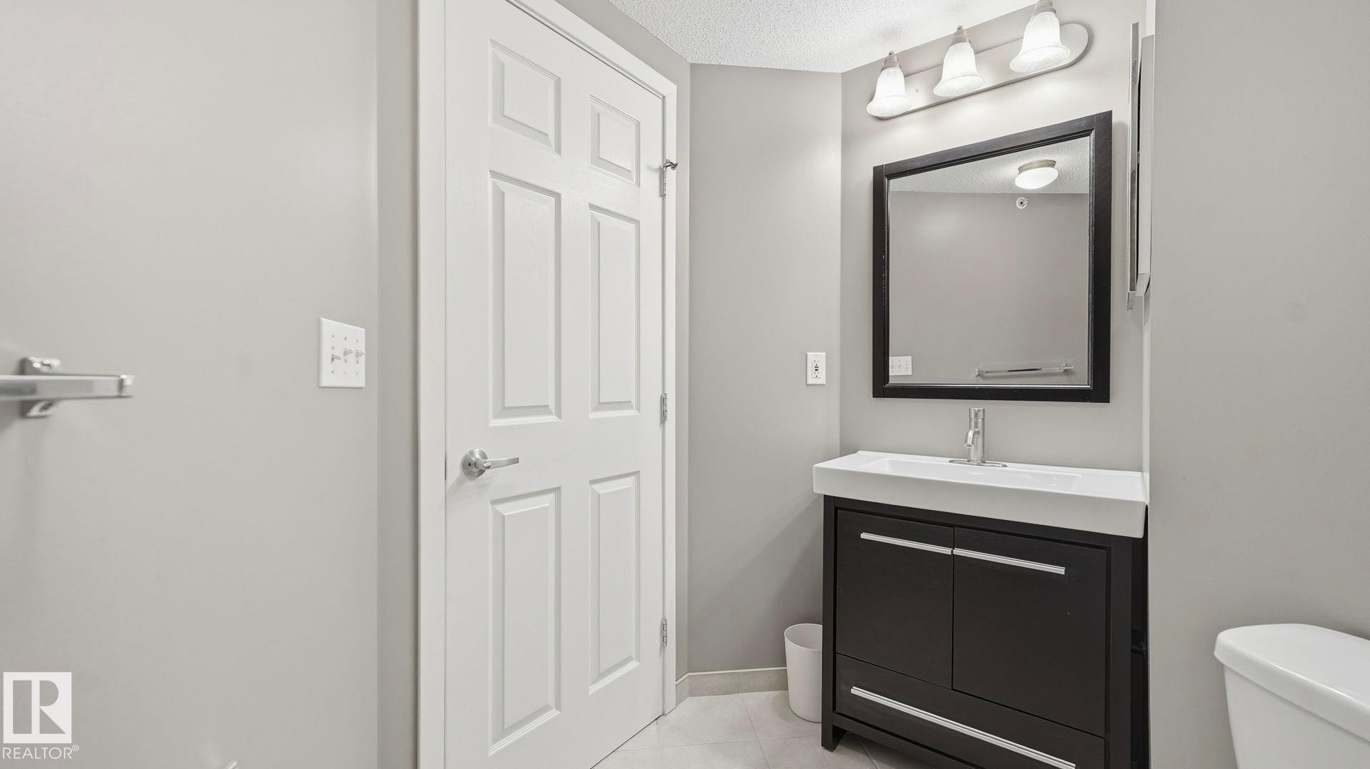 Half bath with vanity, light tile patterned flooring, and a textured ceiling - 401 636 Mcallister Loop, Edmonton, AB - Indoor Photo Showing Bathroom