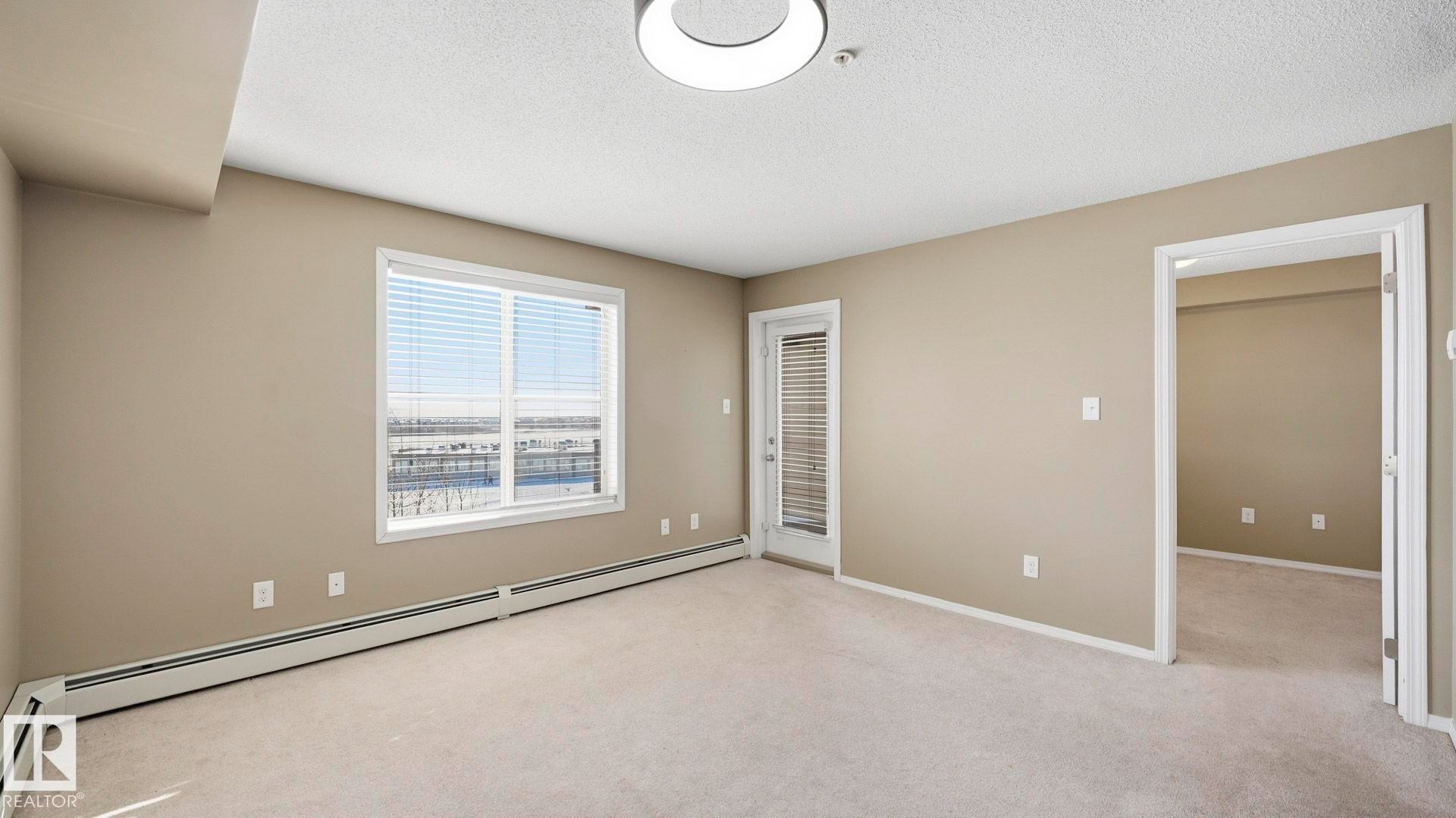 Unfurnished bedroom with light colored carpet, a baseboard heating unit, and a textured ceiling - 319 274 Mcconachie Drive, Edmonton, AB - Indoor Photo Showing Other Room
