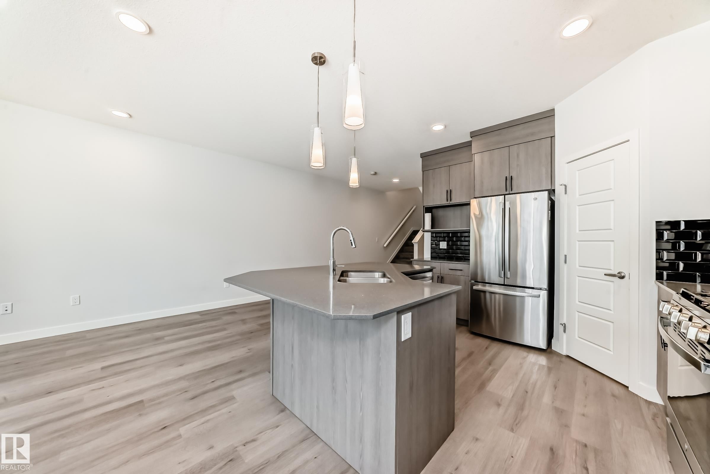 Kitchen with stainless steel appliances, tasteful backsplash, hanging light fixtures, modern cabinets, and light wood-style floors - 2282 Chokecherry Close, Edmonton, AB - Indoor Photo Showing Kitchen With Upgraded Kitchen
