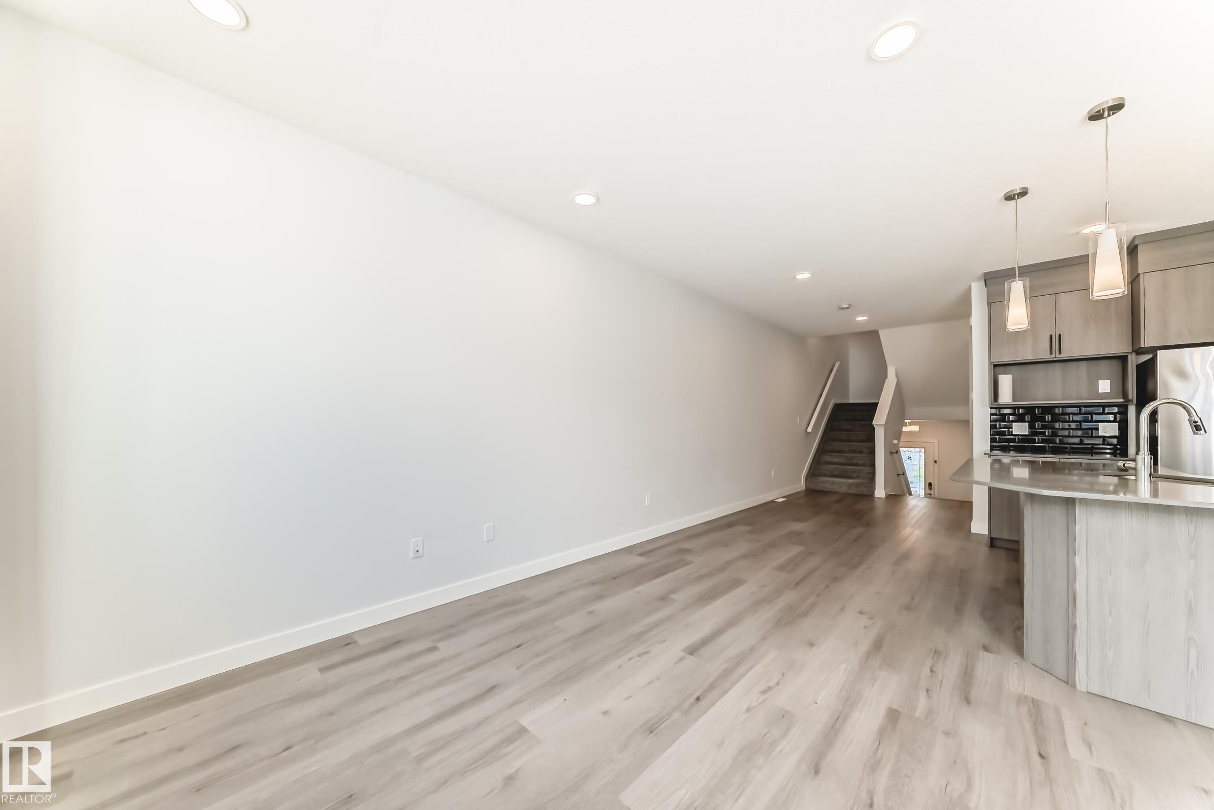 Kitchen with open floor plan, recessed lighting, modern cabinets, hanging light fixtures, and light wood-style floors - 2282 Chokecherry Close, Edmonton, AB - Indoor Photo Showing Kitchen