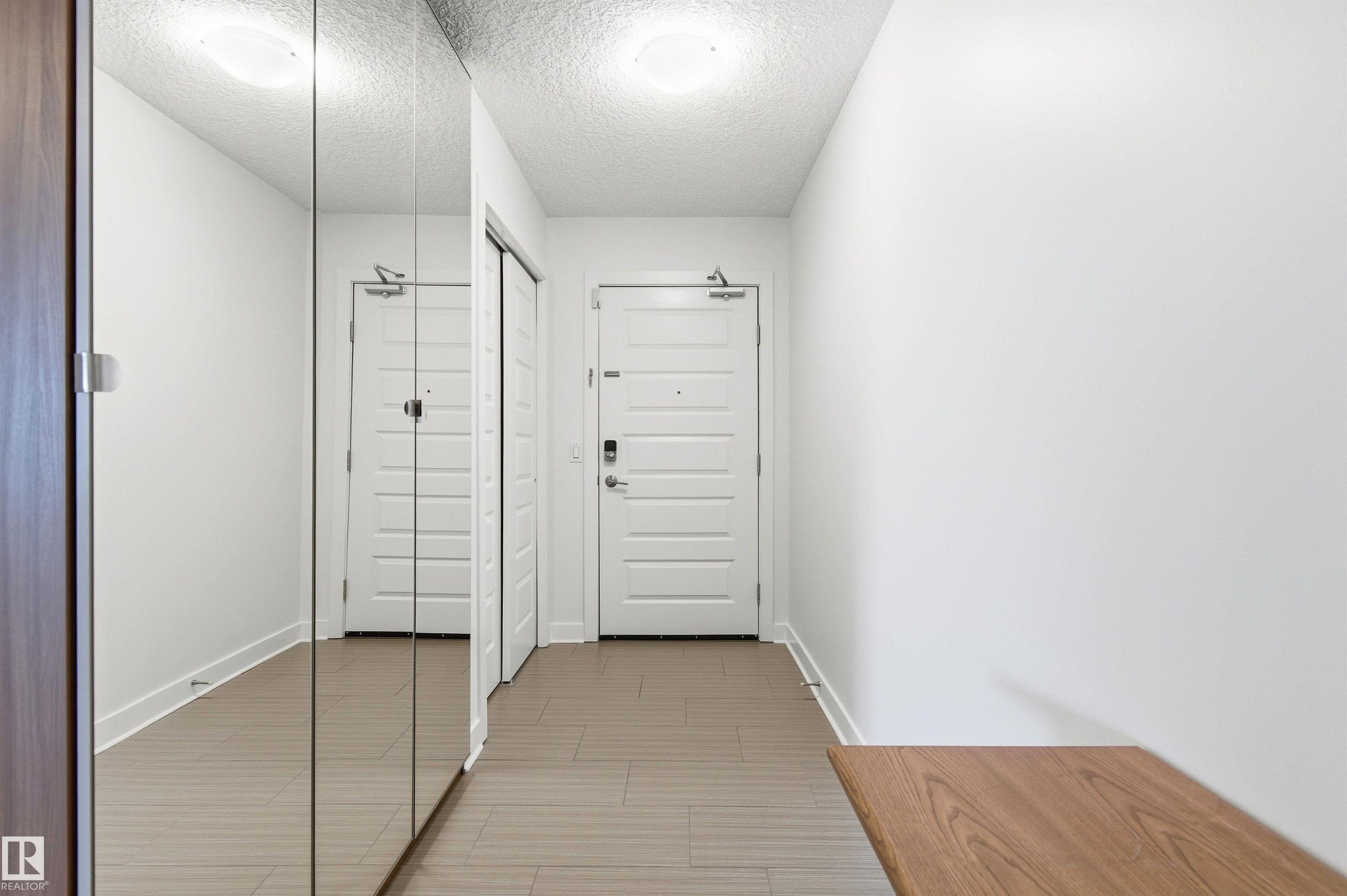 Corridor featuring a textured ceiling and baseboards - 106 1238 Windermere Way, Edmonton, AB - Indoor Photo Showing Other Room