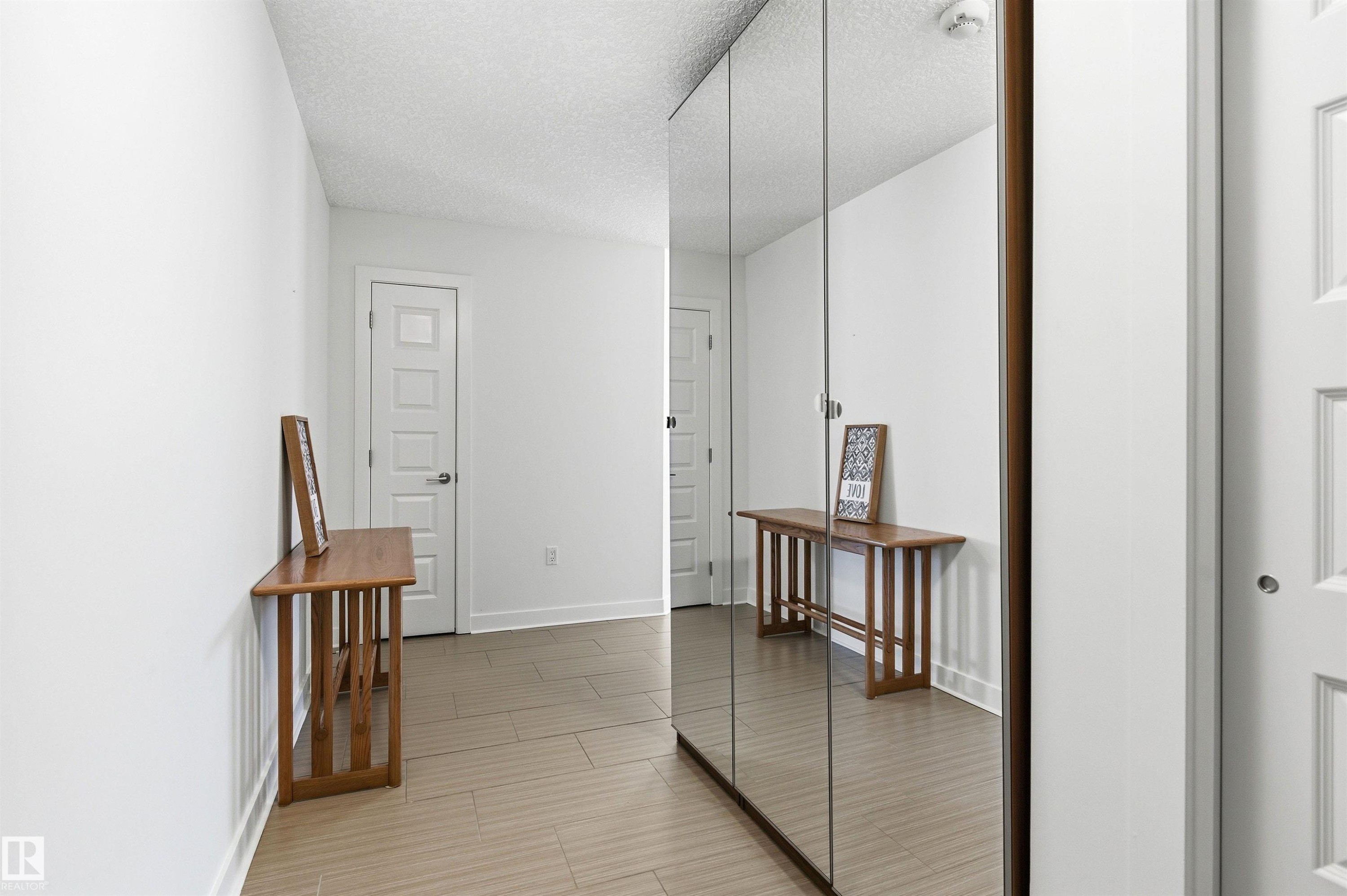 Hallway featuring a textured ceiling and baseboards - 106 1238 Windermere Way, Edmonton, AB - Indoor Photo Showing Other Room
