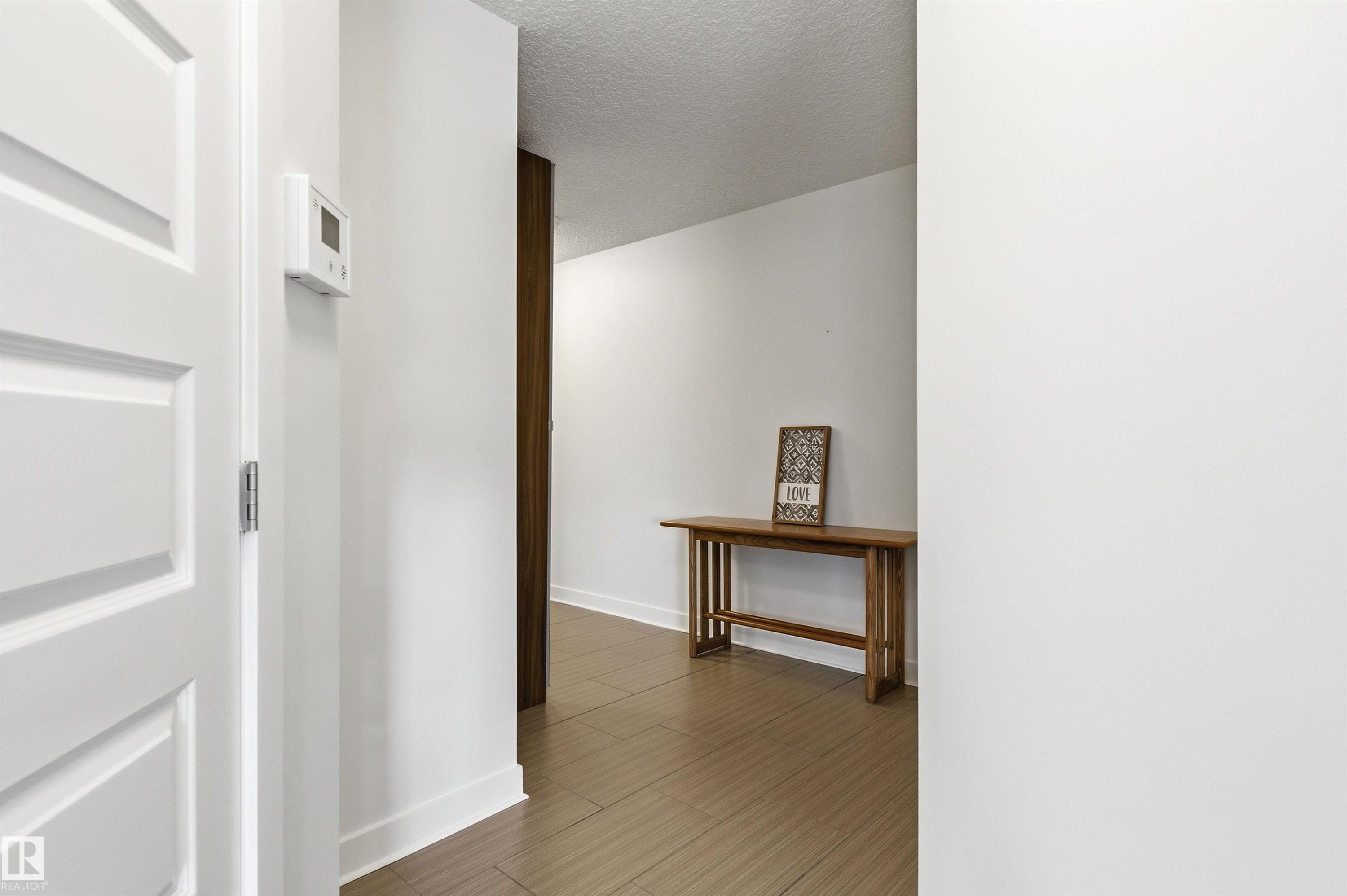 Hall featuring a textured ceiling and wood finished floors - 106 1238 Windermere Way, Edmonton, AB - Indoor Photo Showing Other Room