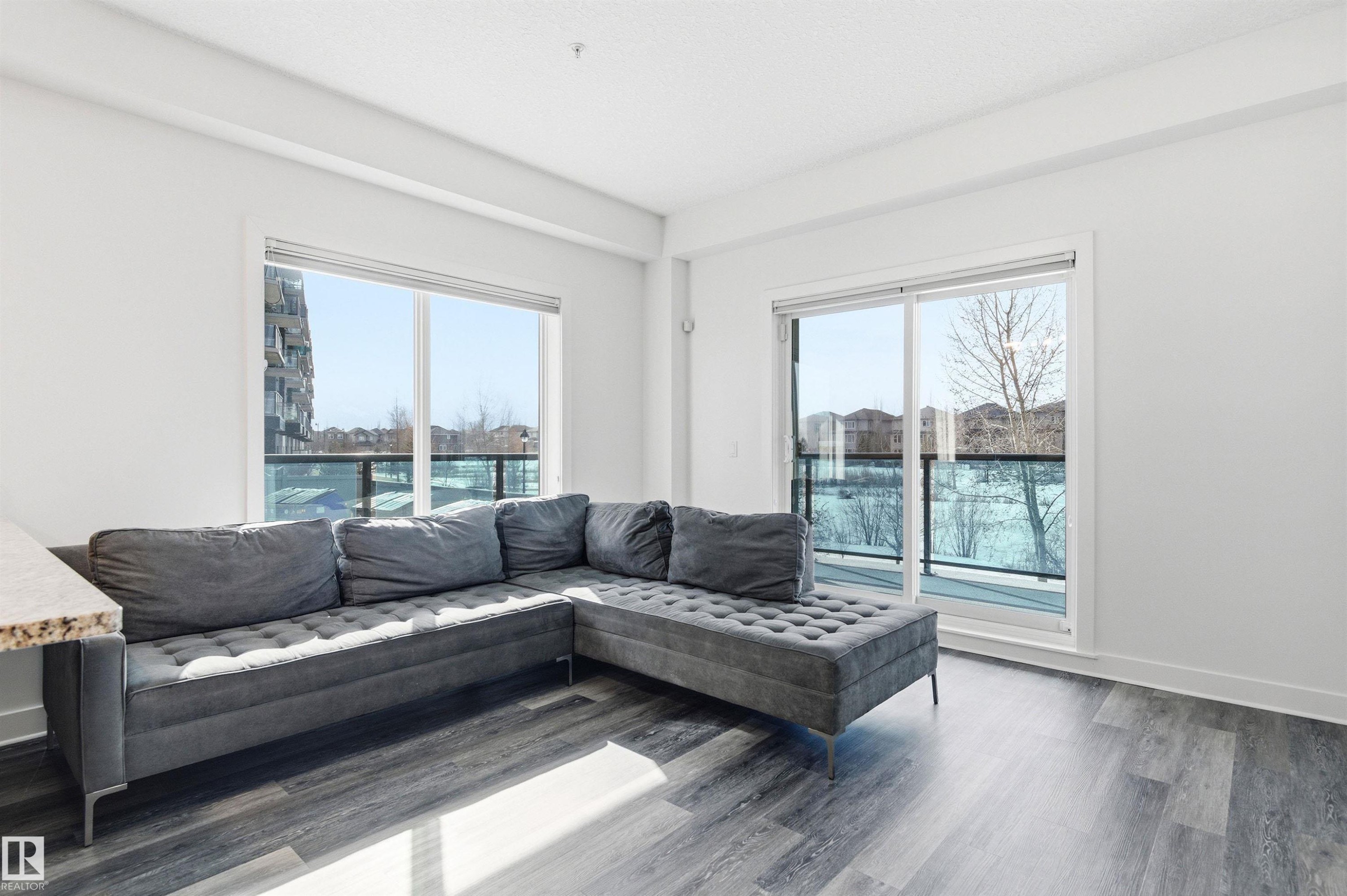 Living area with baseboards and wood finished floors - 106 1238 Windermere Way, Edmonton, AB - Indoor Photo Showing Living Room