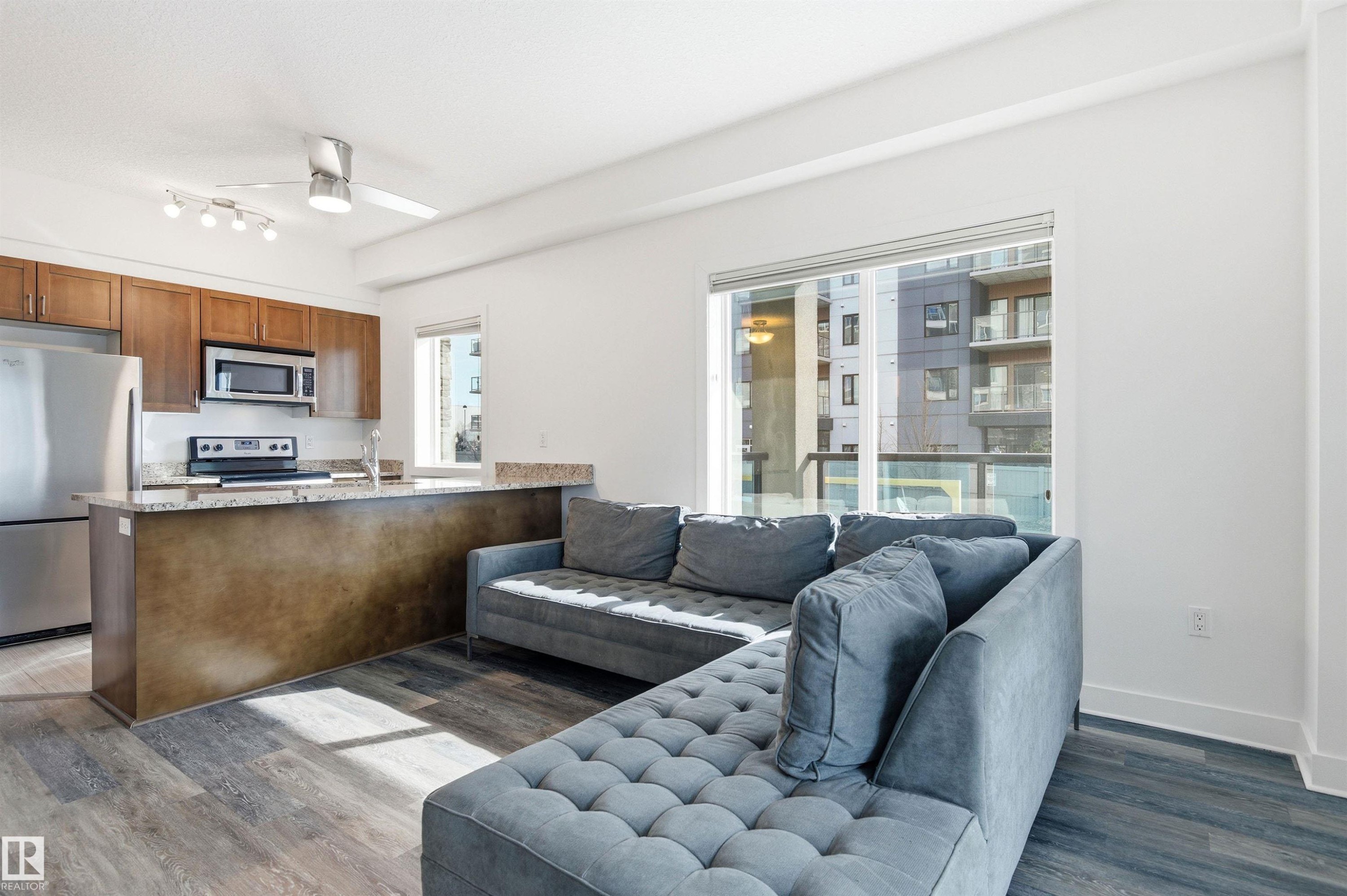 Living room featuring a ceiling fan and dark wood finished floors - 106 1238 Windermere Way, Edmonton, AB - Indoor