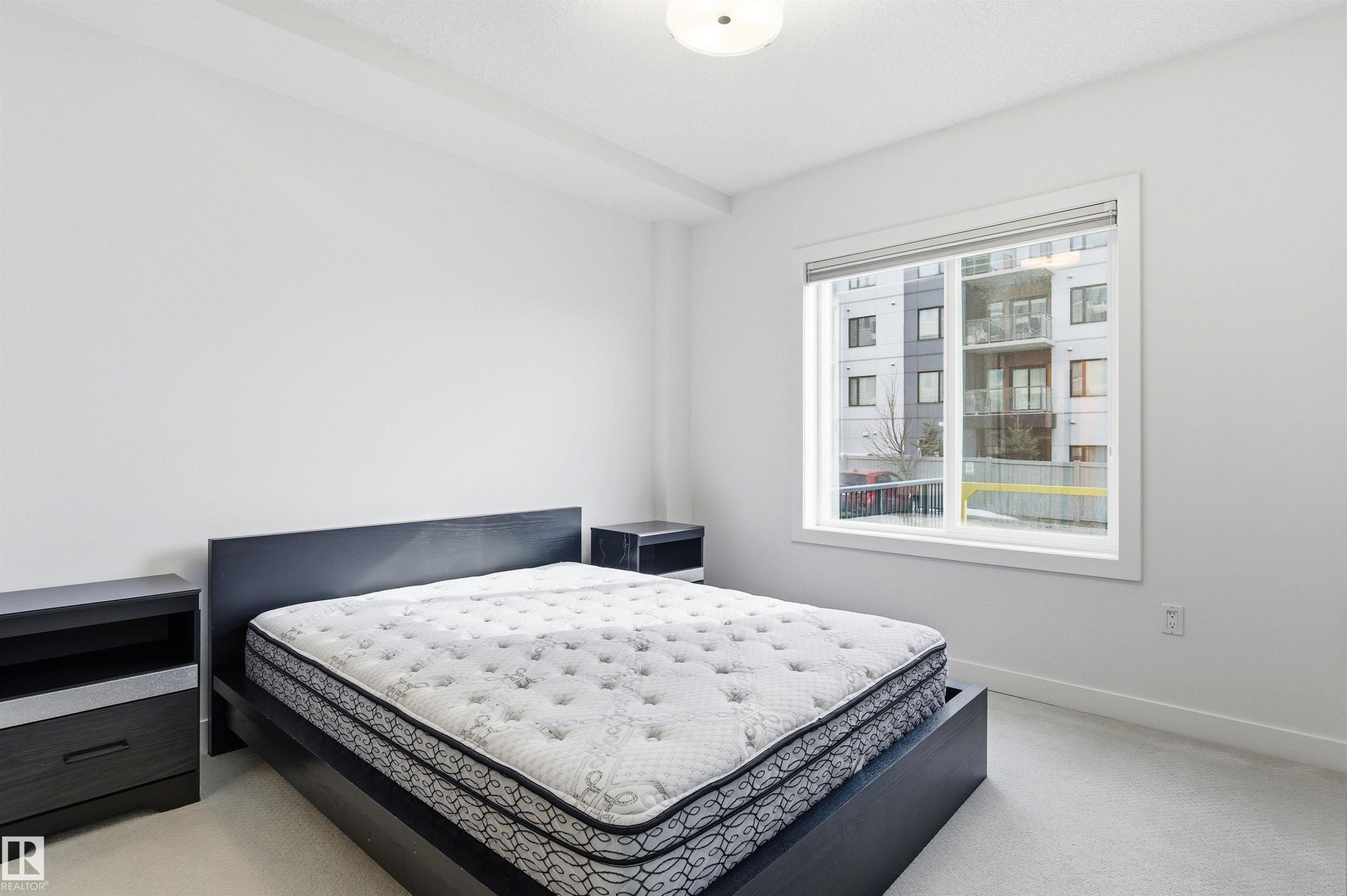 Bedroom with light carpet and baseboards - 106 1238 Windermere Way, Edmonton, AB - Indoor Photo Showing Bedroom