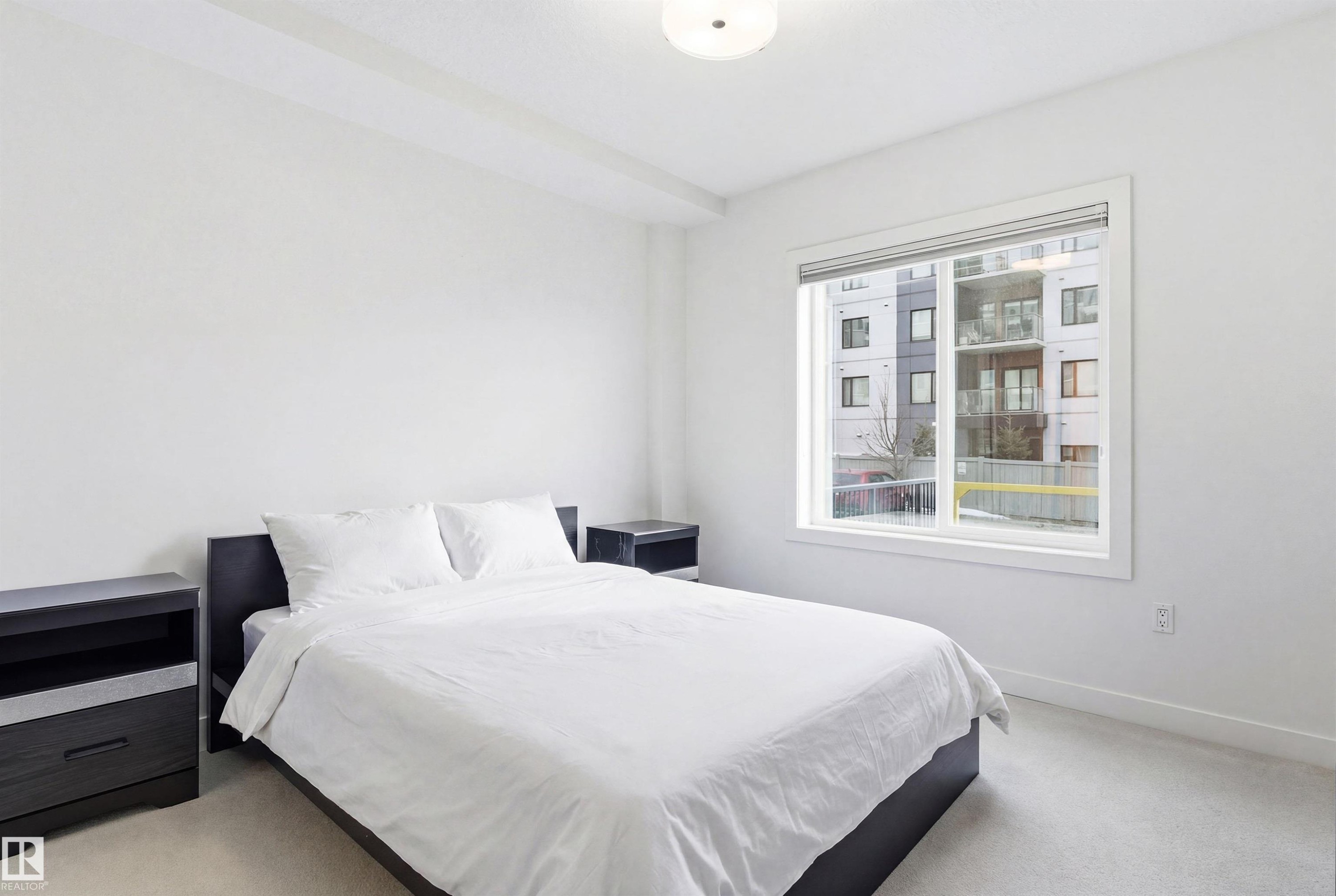 Bedroom featuring light colored carpet and baseboards - 106 1238 Windermere Way, Edmonton, AB - Indoor Photo Showing Bedroom