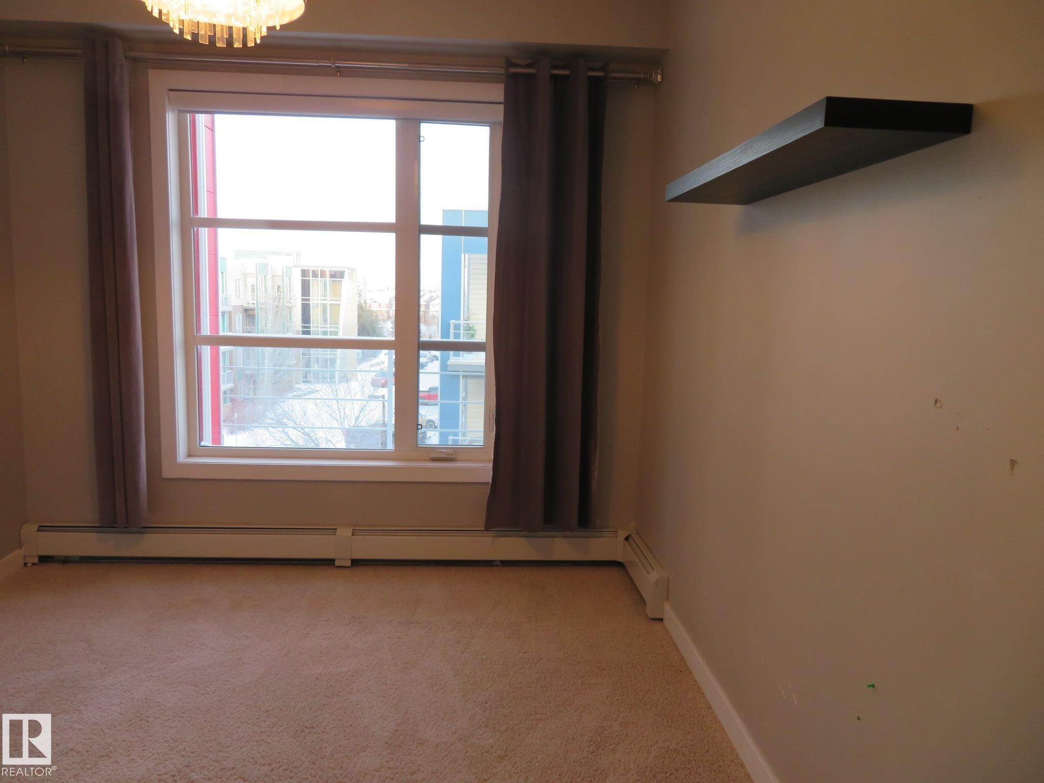 Spare room with light carpet and a chandelier - 415 2590 Anderson Way, Edmonton, AB - Indoor Photo Showing Other Room