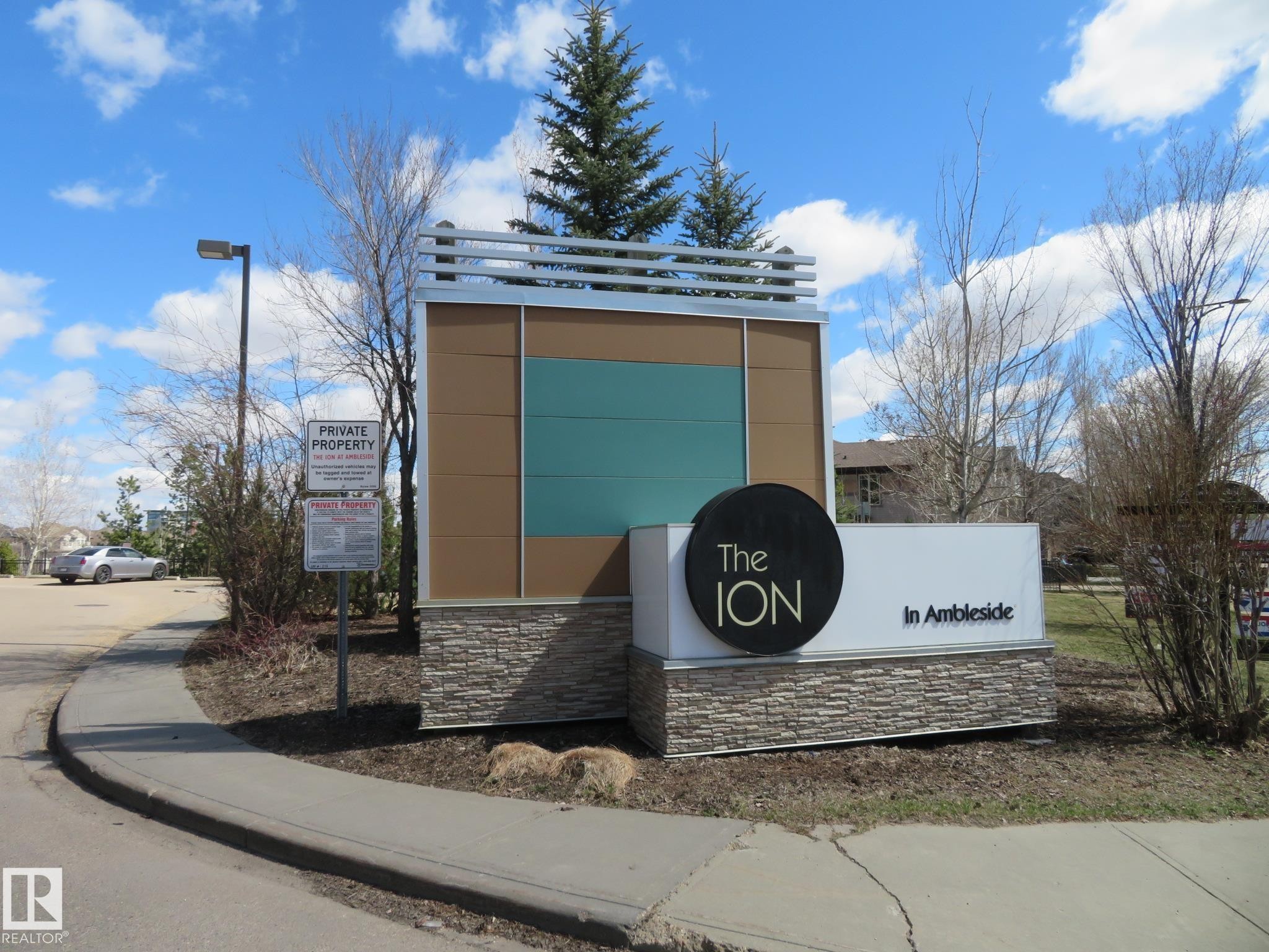 Modern community signage featuring stone accents, a contemporary metal and panel design, and integrated landscaping - 415 2590 Anderson Way, Edmonton, AB - Outdoor