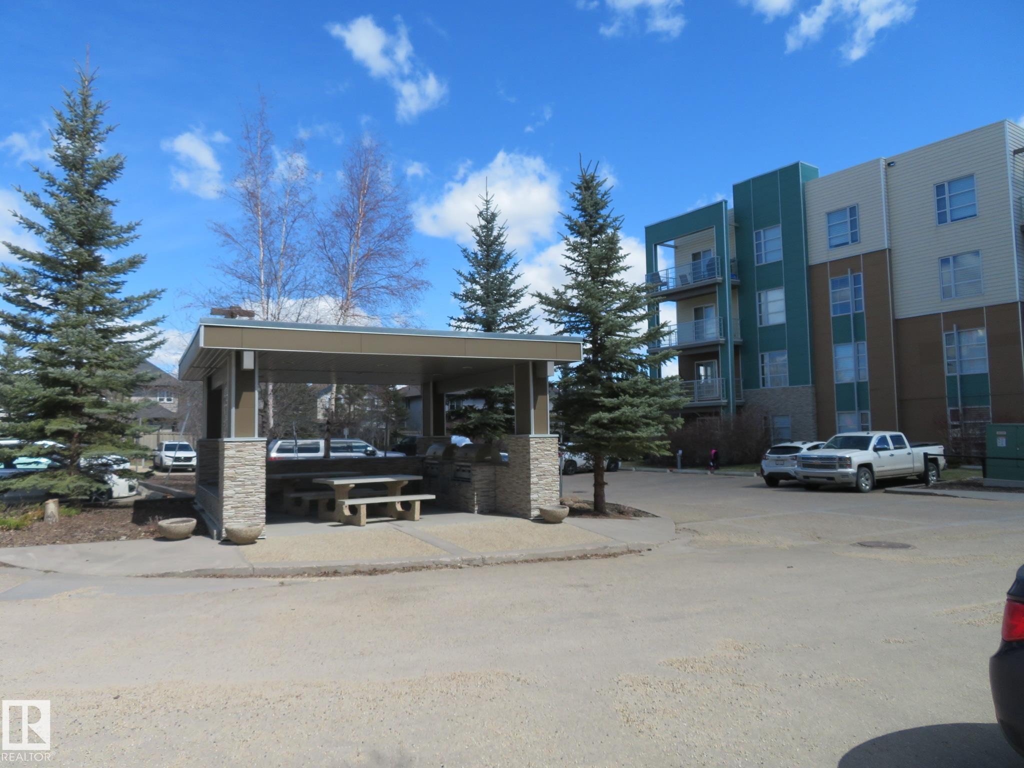 Outdoor covered area featuring a stone-faced base, composite roof, and an integrated picnic table - 415 2590 Anderson Way, Edmonton, AB - Outdoor